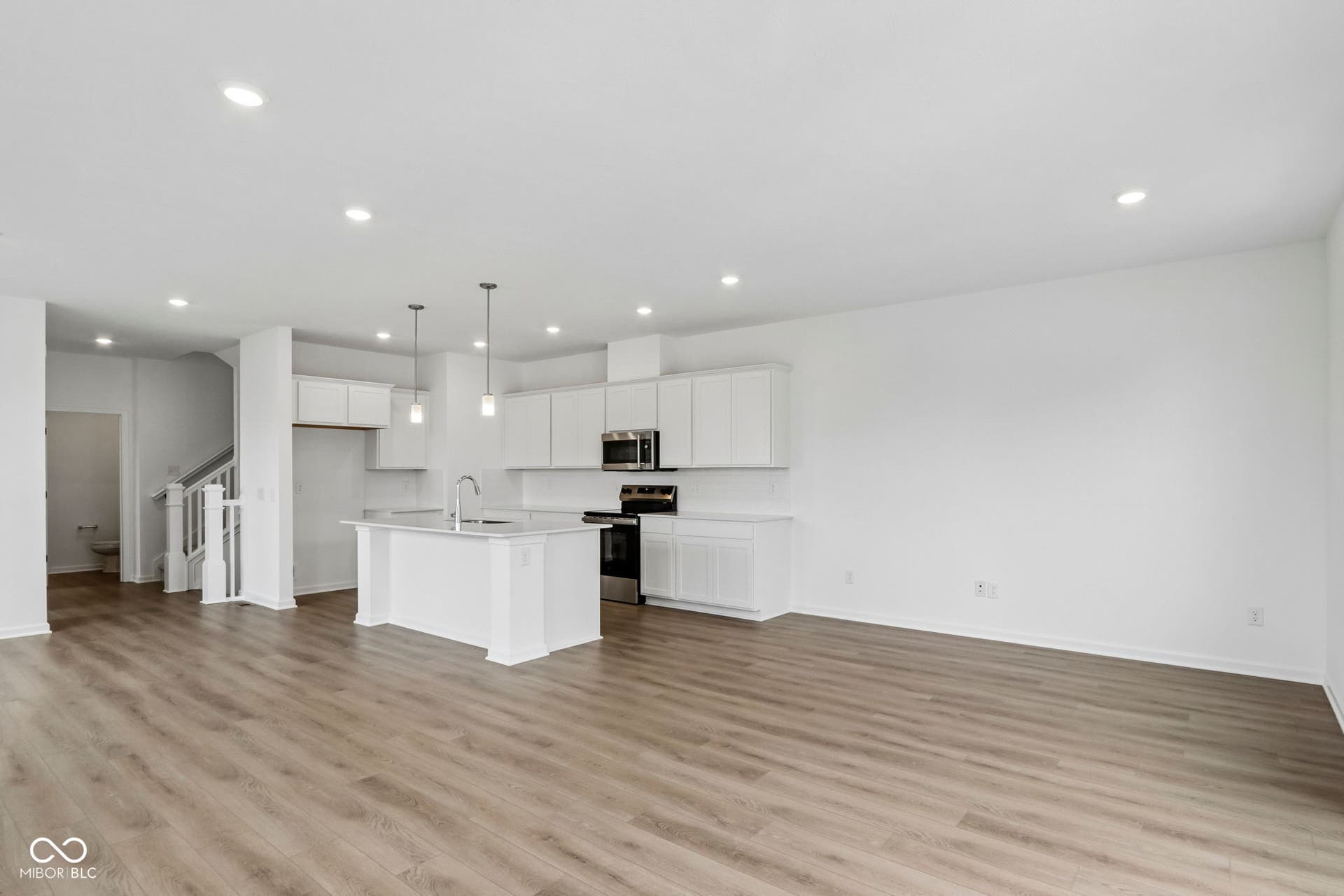 5748 Arcade Boulevard, McCordsville, IN 46055 Open-concept living area featuring wood-finish flooring, recessed lighting, and a kitchen island with pendant lighting