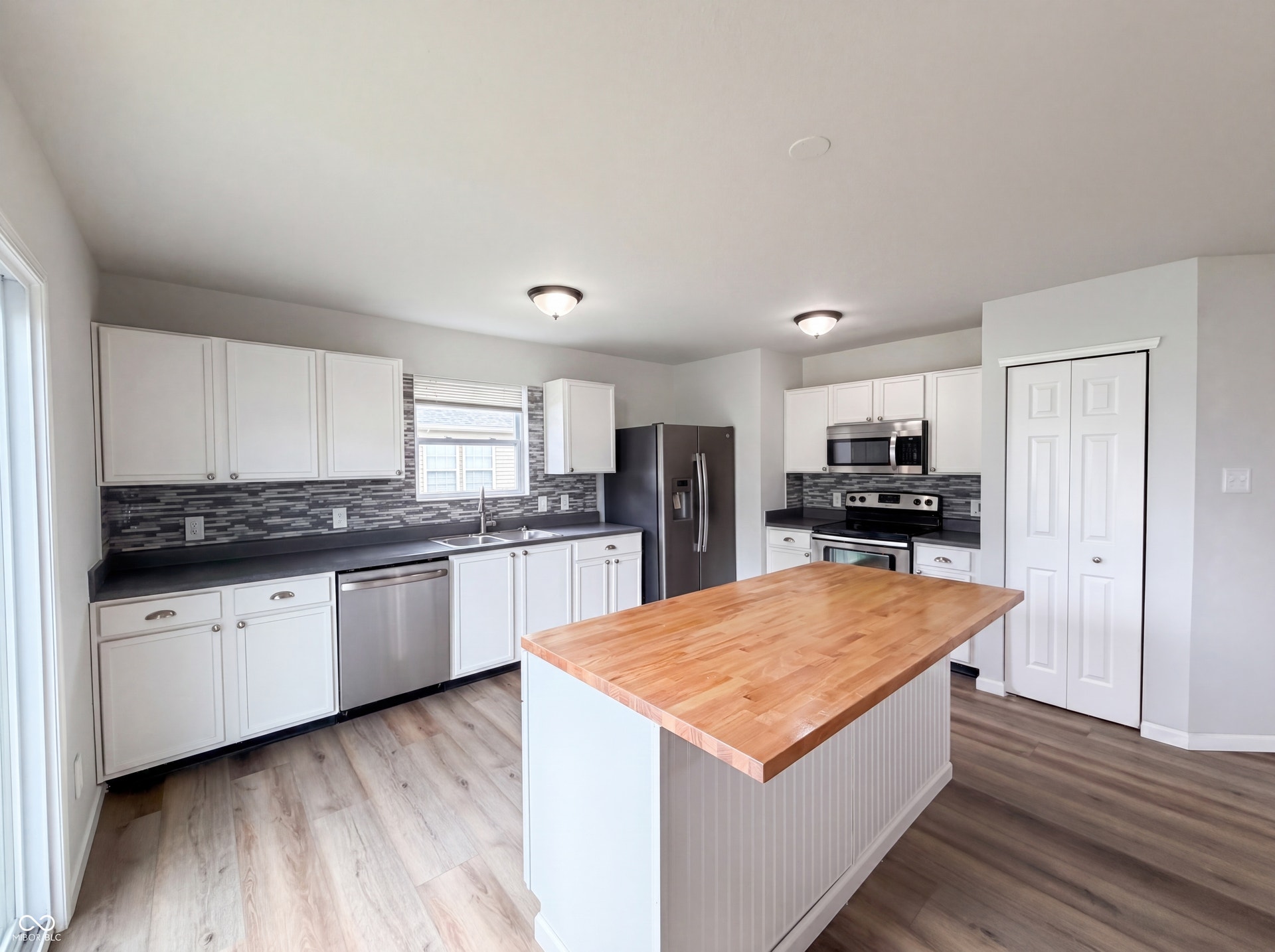 526 Bourneside Drive, Greenfield, IN 46140 Kitchen featuring a wood-finish island, white cabinetry, dark countertops, a mosaic tile backsplash, and wood-finish flooring