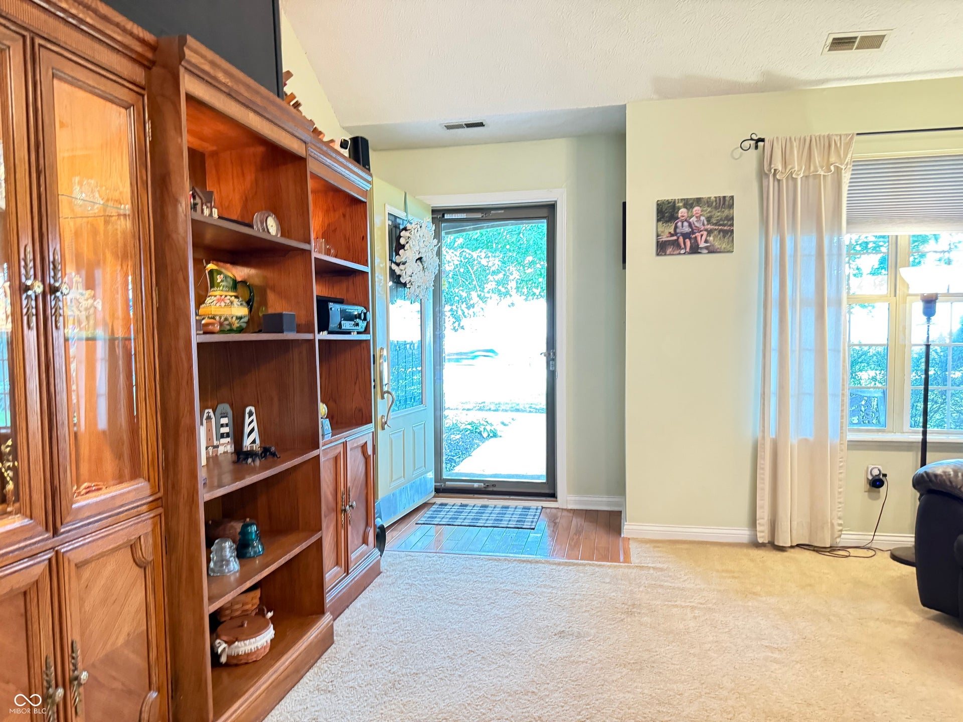 2117 Witt Road, Lebanon, IN 46052 Hardwood flooring at entry, built-in display cabinetry, light-toned wall paint, large window with natural light, and plush carpeting