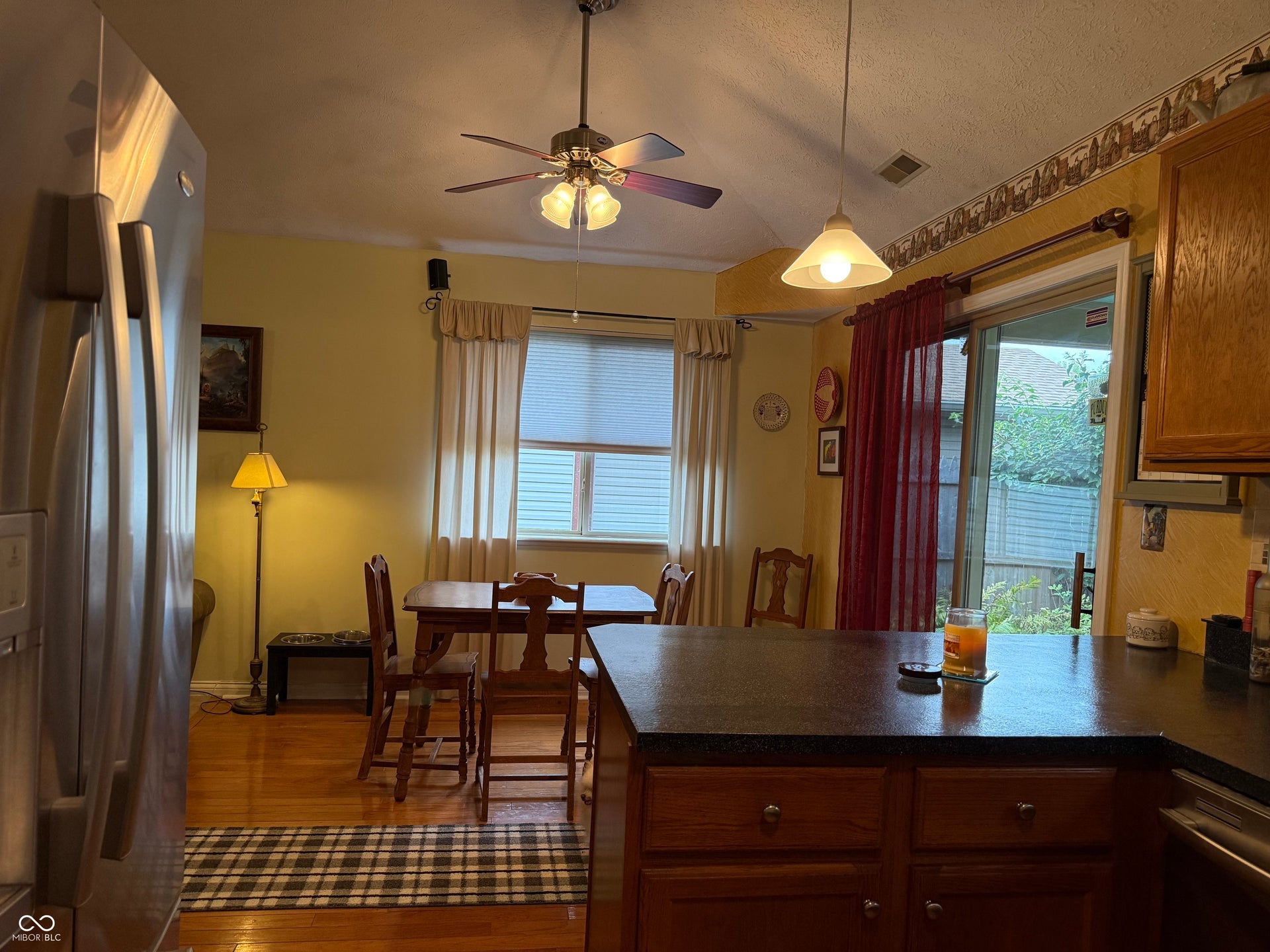 2117 Witt Road, Lebanon, IN 46052 Hardwood flooring, ceiling fan with light fixture, sliding glass door, kitchen island with built-in cabinetry, and pendant lighting