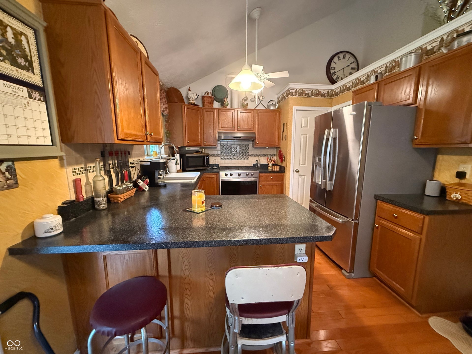 2117 Witt Road, Lebanon, IN 46052 Kitchen featuring wood-finish cabinetry, stainless steel appliances, a breakfast bar, a tiled backsplash, and vaulted ceilings