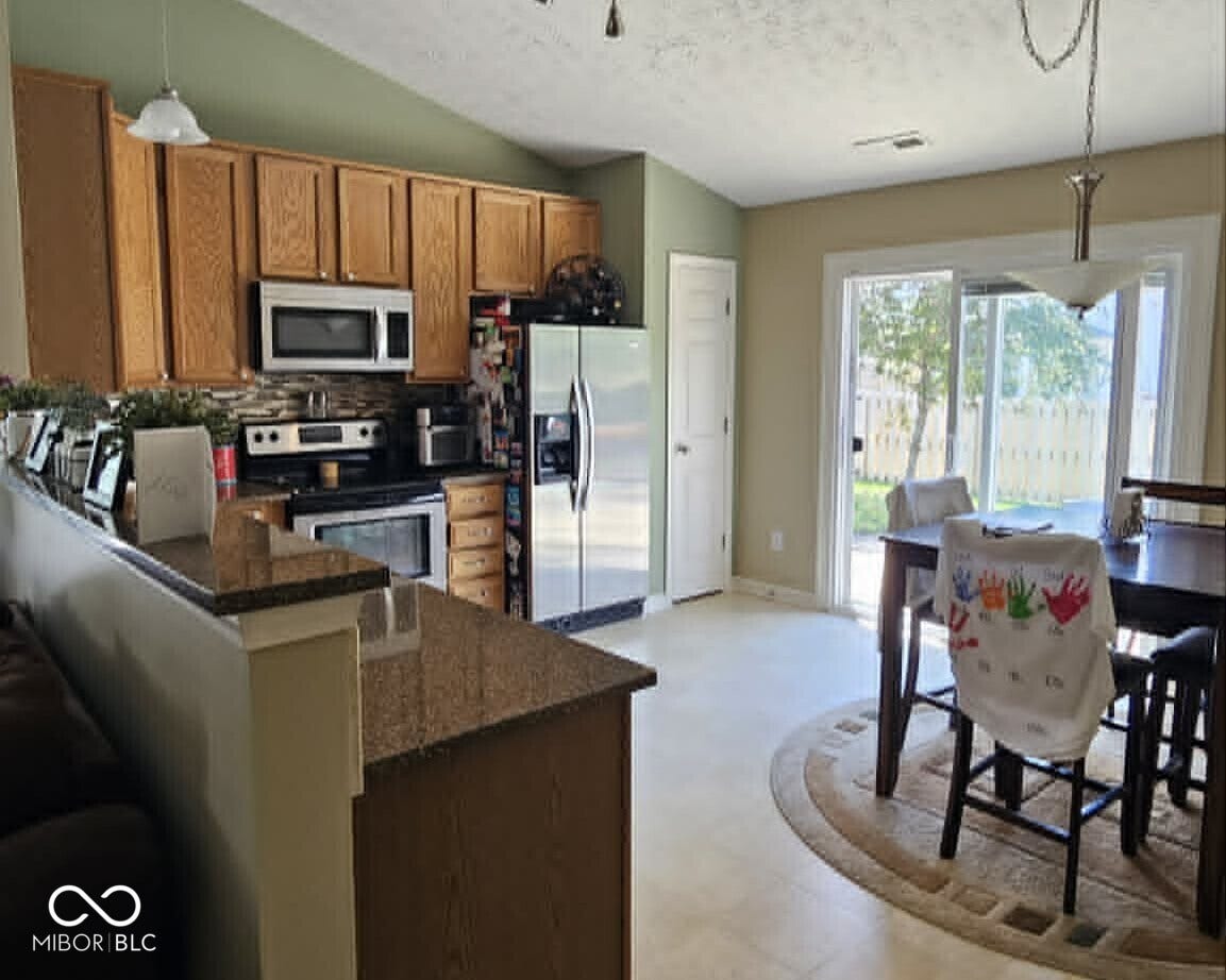 Eat-in Kitchen featuring wood-finish cabinetry, stainless steel appliances, and a tiled backsplash