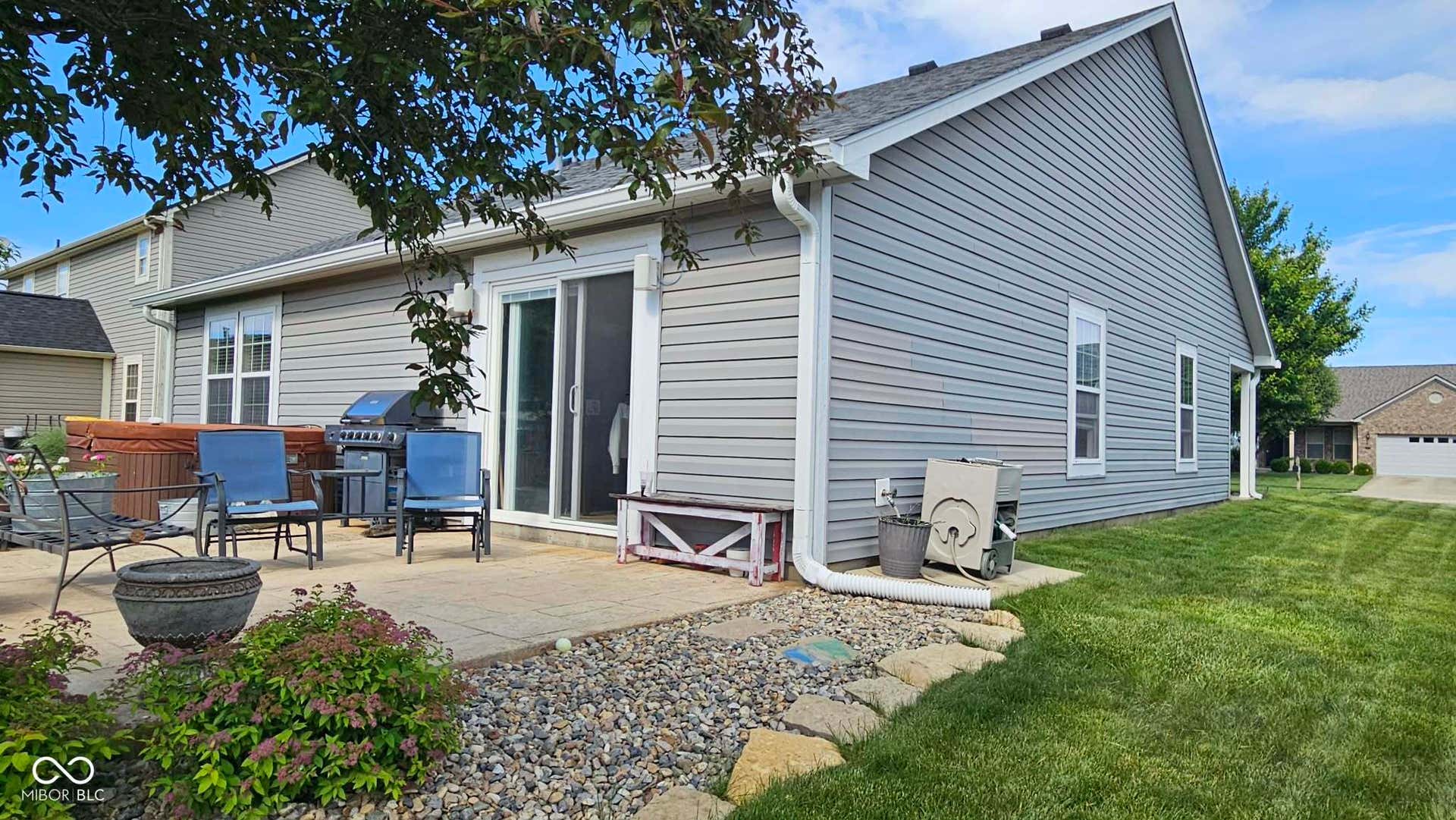 Spacious gray siding exterior with a large patio area