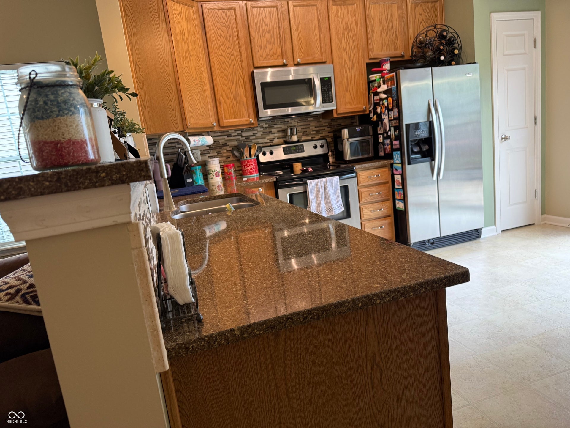 Kitchen featuring wood cabinetry, stainless steel appliances, speckled countertops, and a tiled backsplash