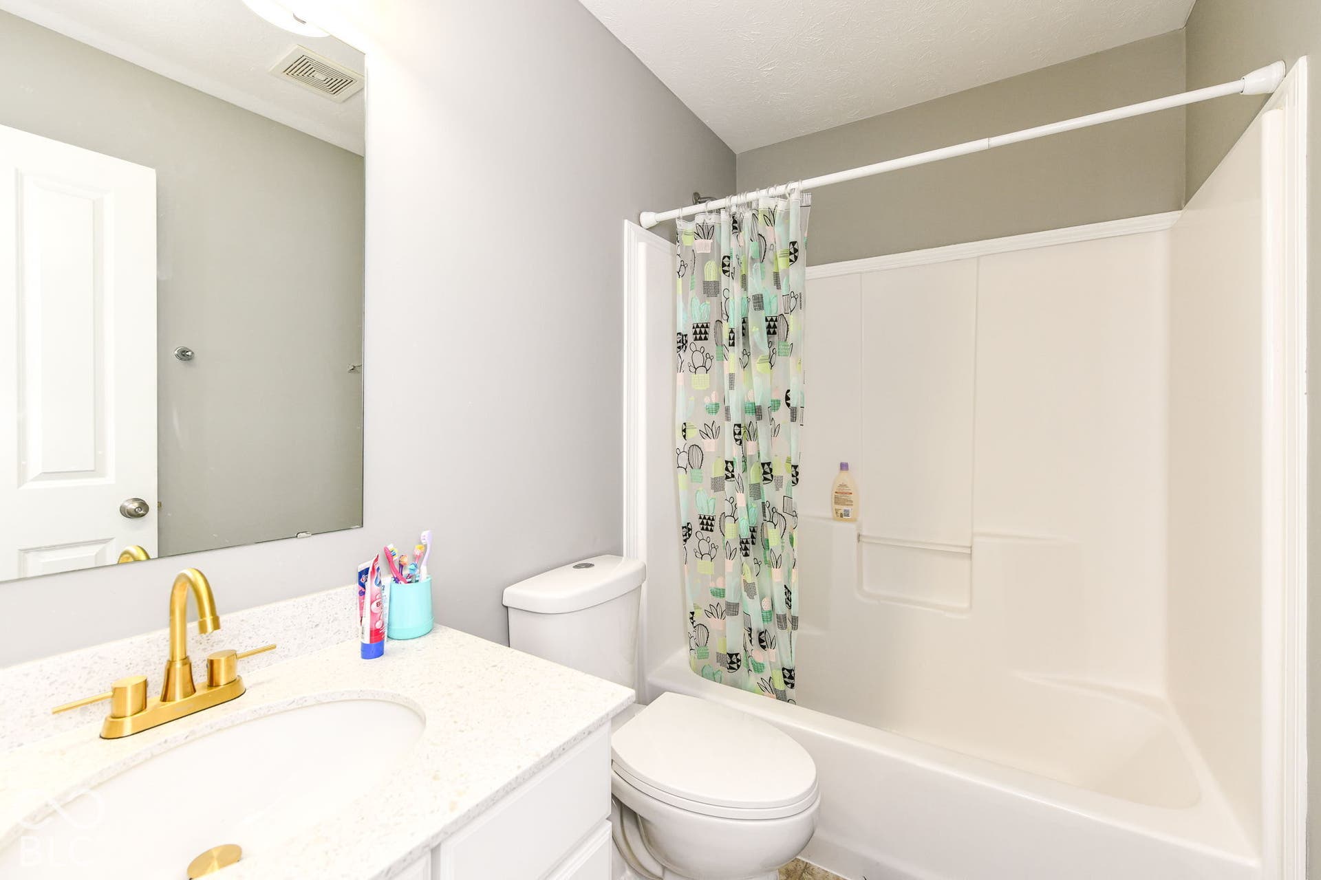 White vanity with a light-toned countertop, a gold-finish faucet, and an integrated sink