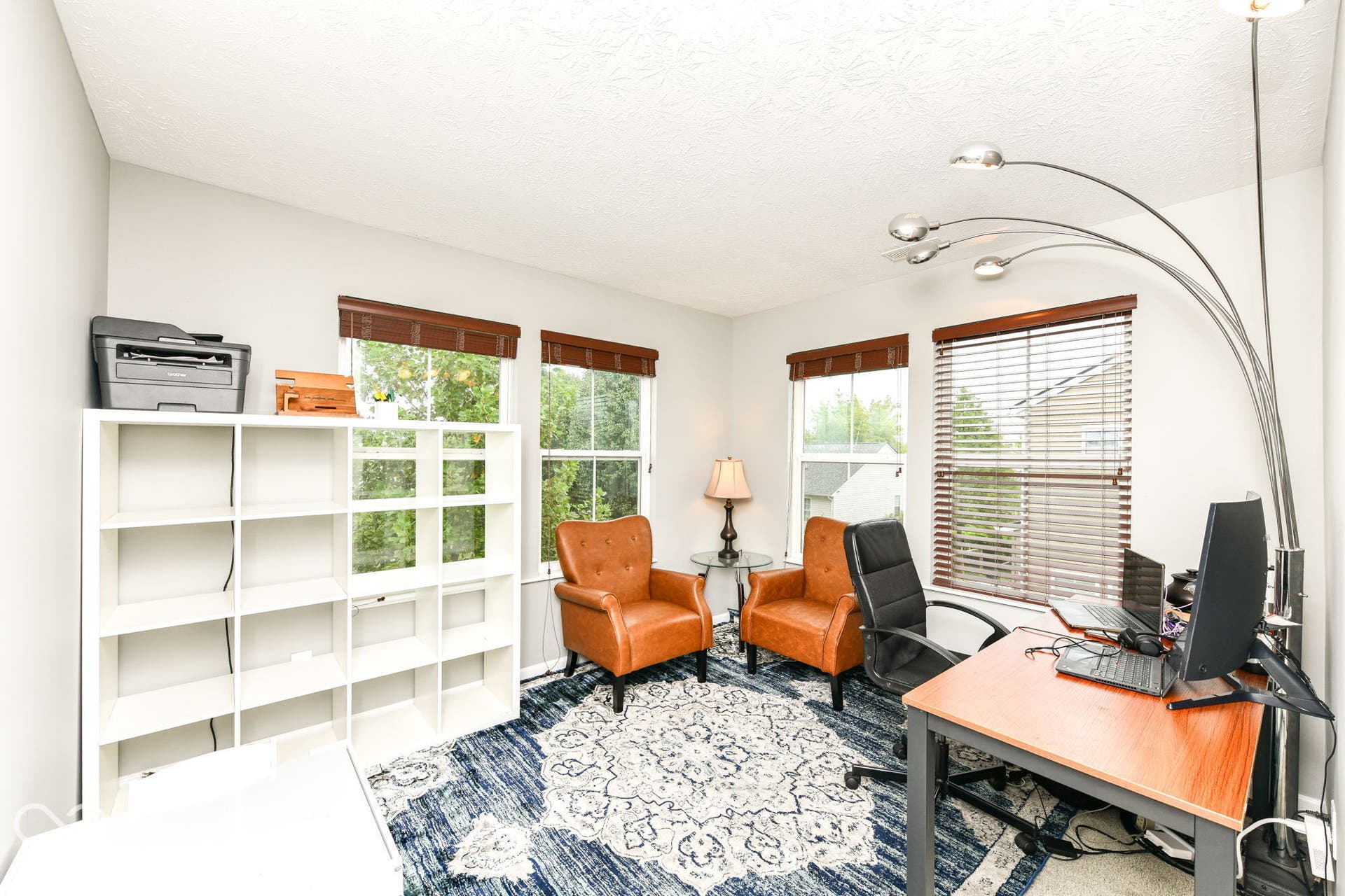 Room featuring multiple windows with blinds, white textured walls, and recessed lighting