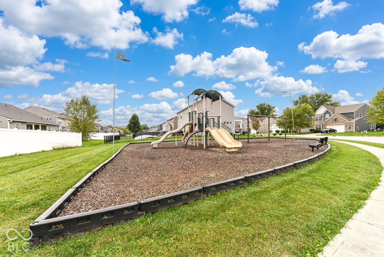Community playground featuring a multi-level play structure, two slides, swings, and benches