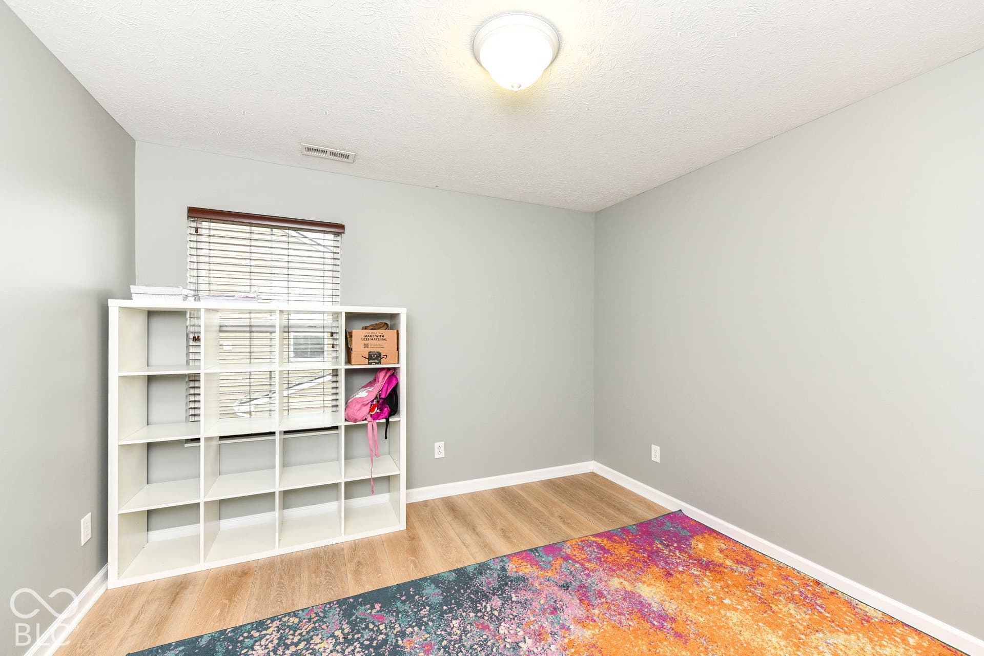 Light wood-finish flooring, neutral wall paint, and a single window with blinds