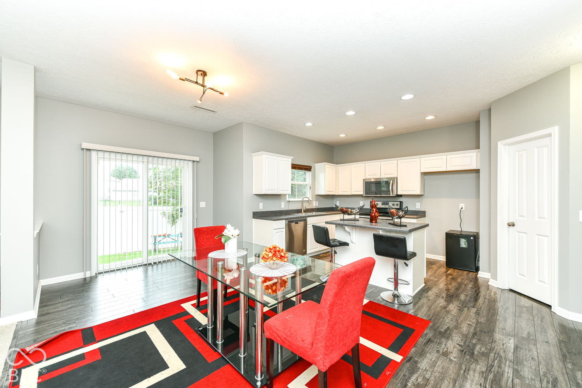 Kitchen with white cabinetry, dark countertops, stainless steel appliances, and wood-finish flooring