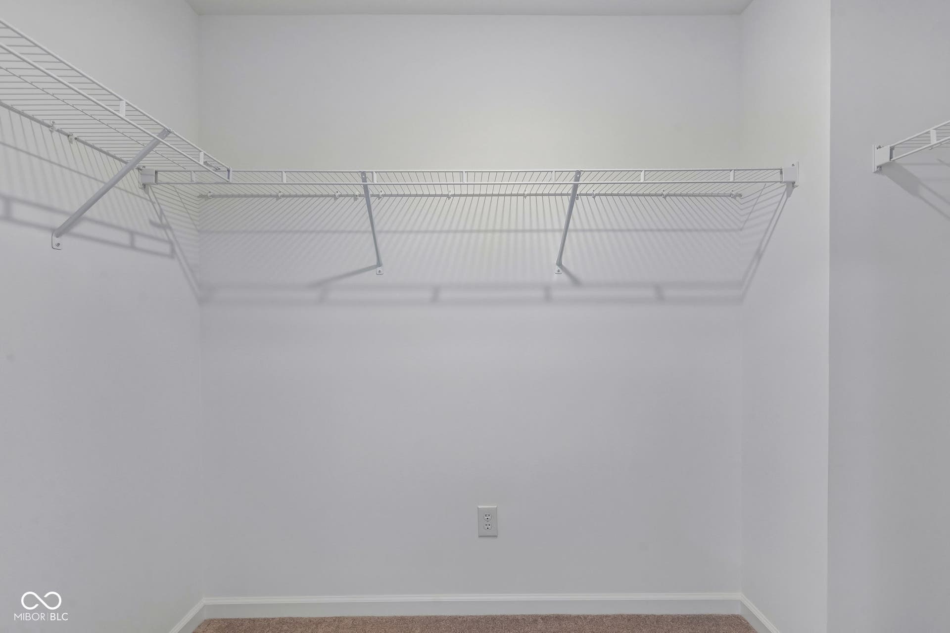Walk-in closet with white wire shelving and plush carpet flooring