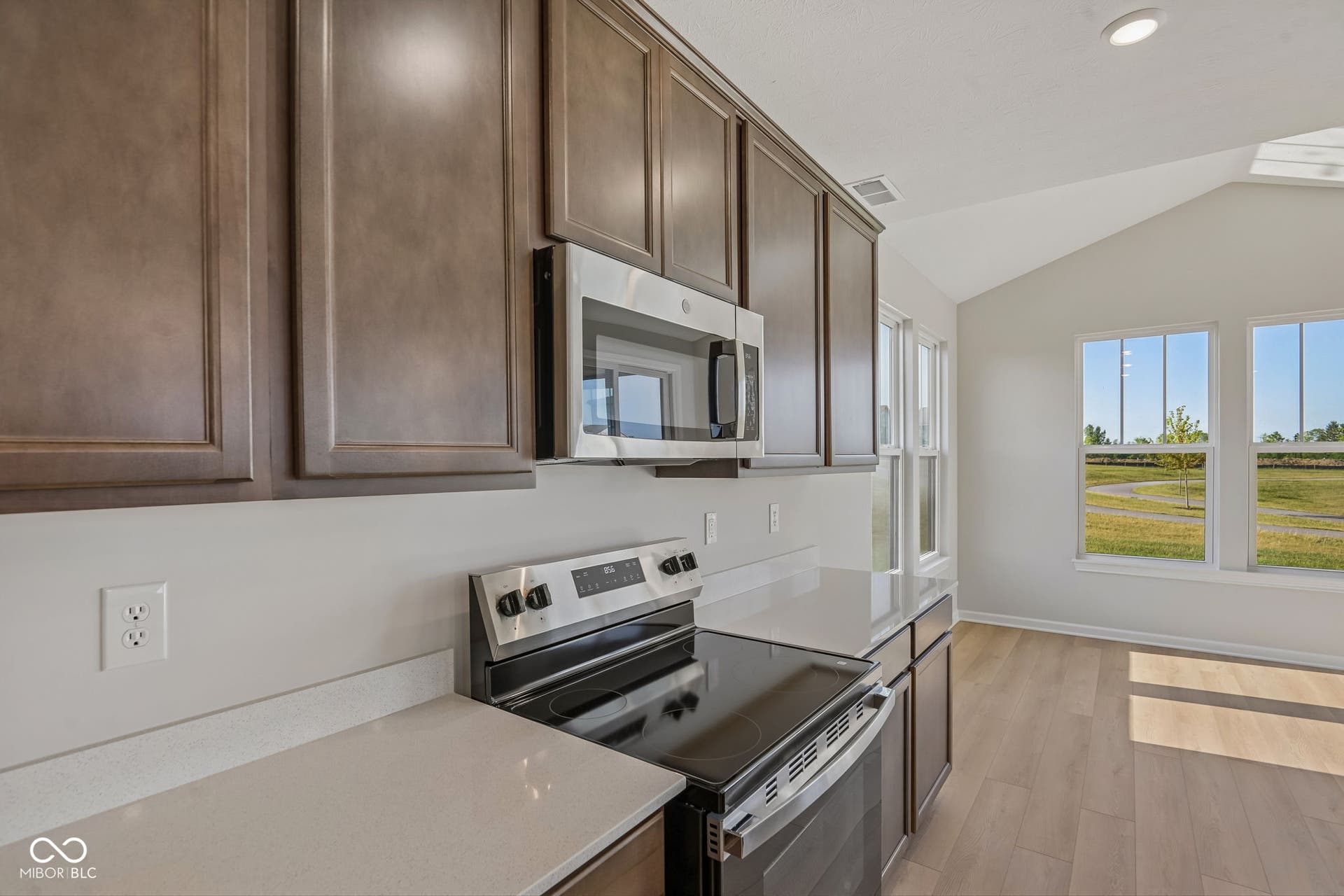 Kitchen featuring stainless steel appliances, dark wood cabinetry, and light countertops