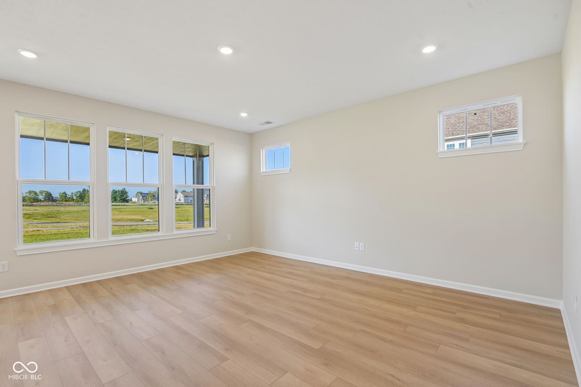 Spacious room featuring wood-finish flooring, recessed lighting, and multiple windows