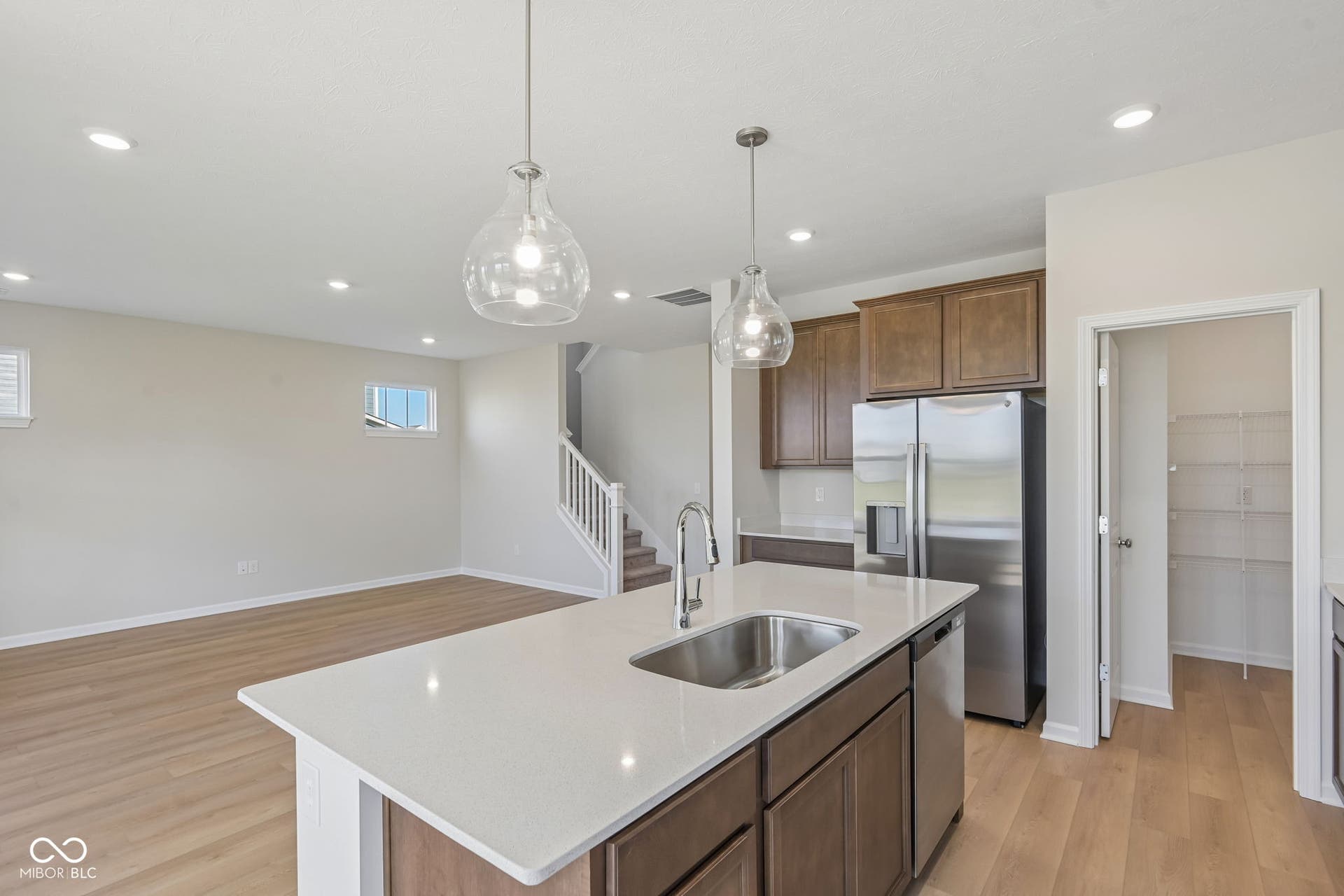 Kitchen island with a stainless steel sink, quartz-style countertop, and pendant lighting
