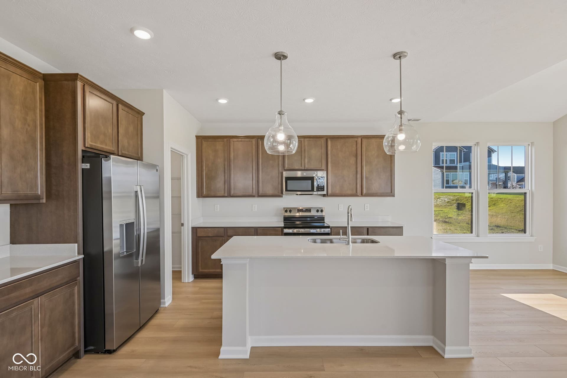 Kitchen featuring a central island with an undermount sink, pendant lighting, stainless steel appliances, and wood-finish cabinetry