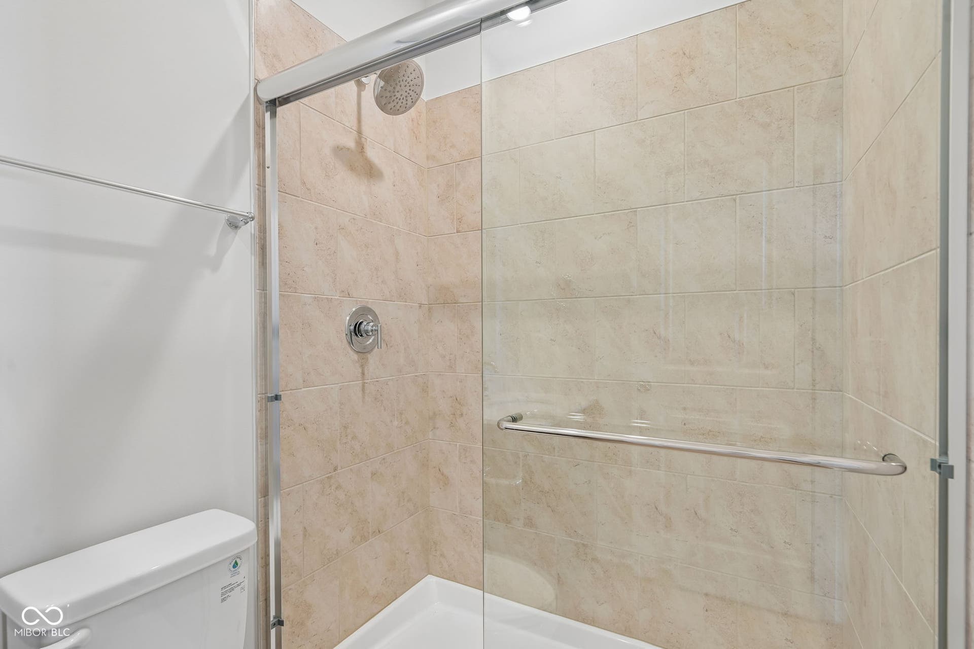 Glass-enclosed shower with ceramic tile surround, chrome fixtures, and a white shower pan