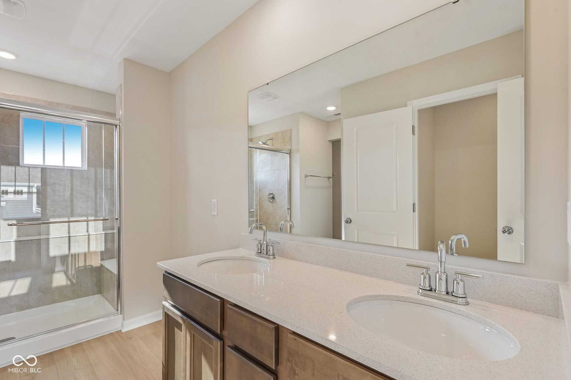 Dual vanity with undermount sinks and chrome fixtures, set against a large frameless mirror