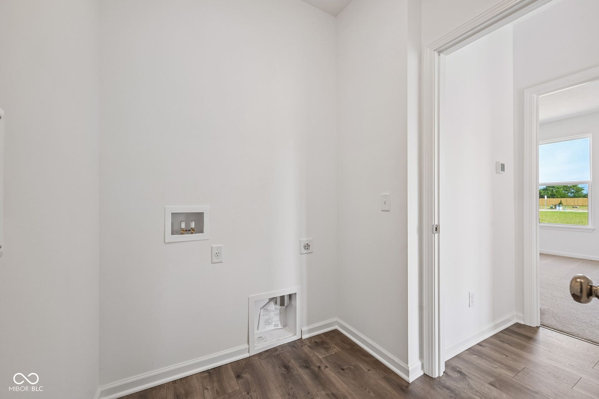 Laundry area featuring wood-finish flooring and white baseboards