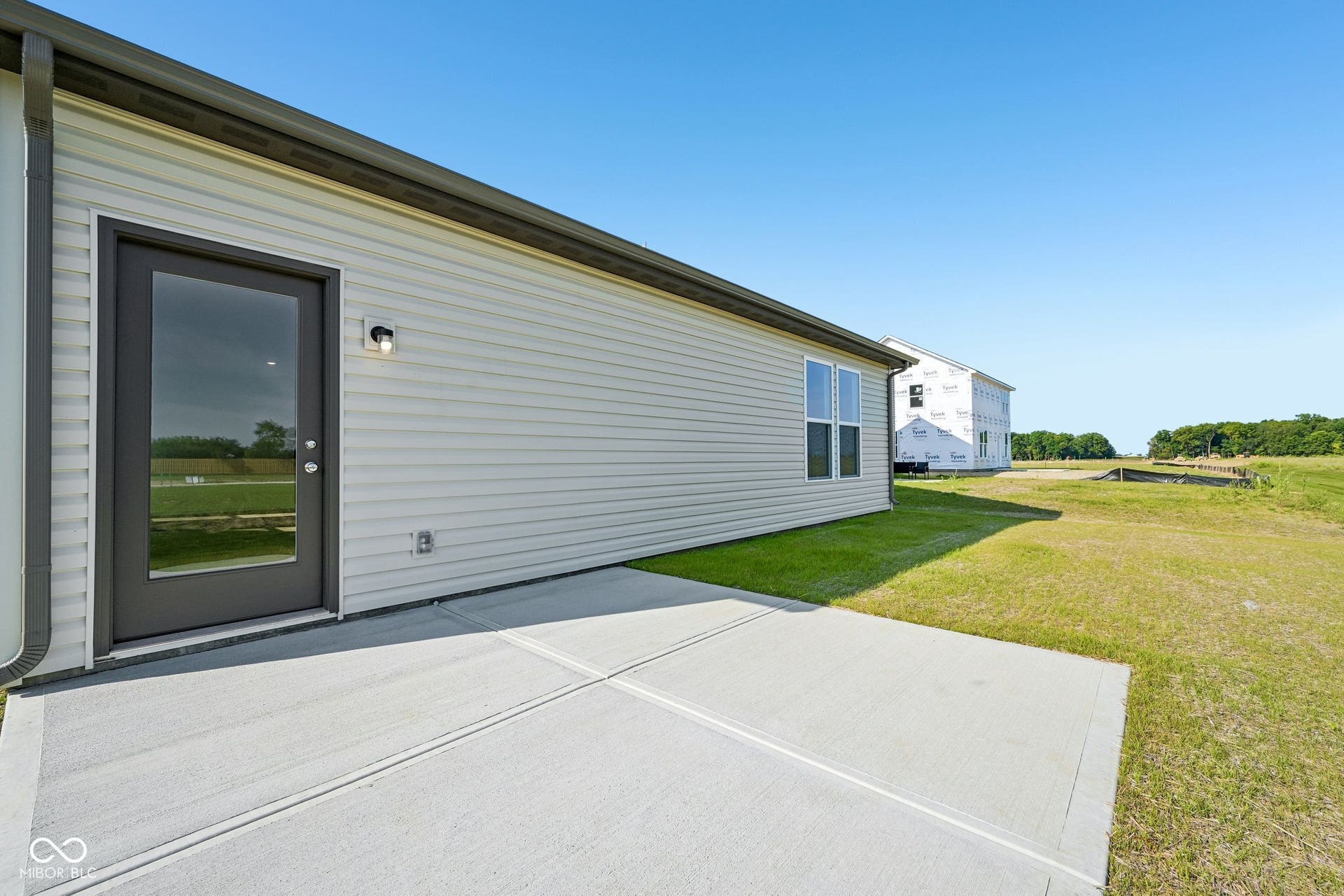 Rear concrete patio with clear glass door and outdoor lighting