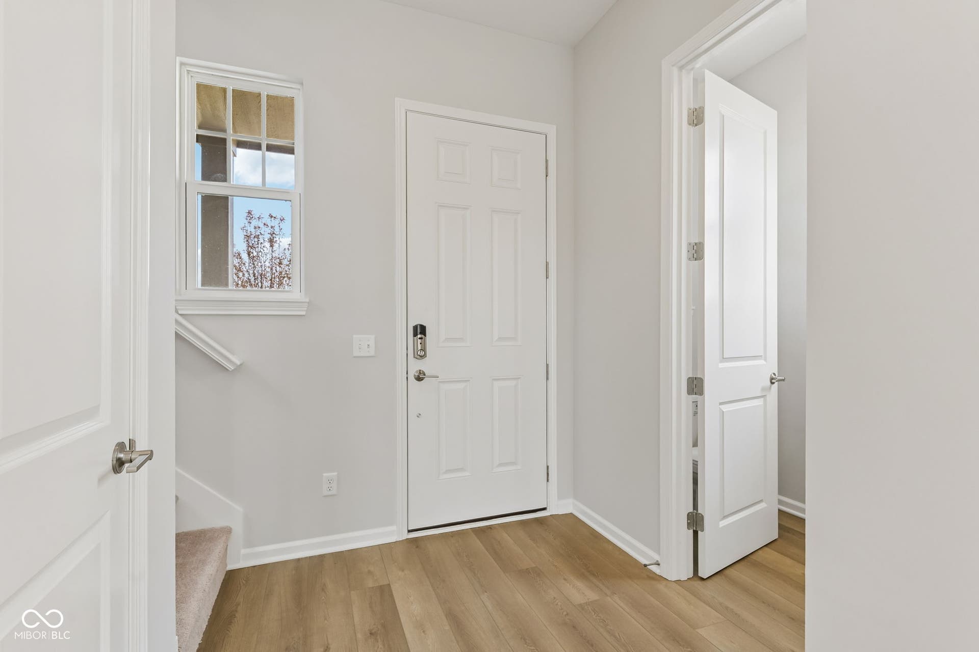 15762 Showdown Road, Noblesville, IN 46060 Entryway featuring wood-finish flooring, a white paneled entry door with smart lock, and a double-hung window