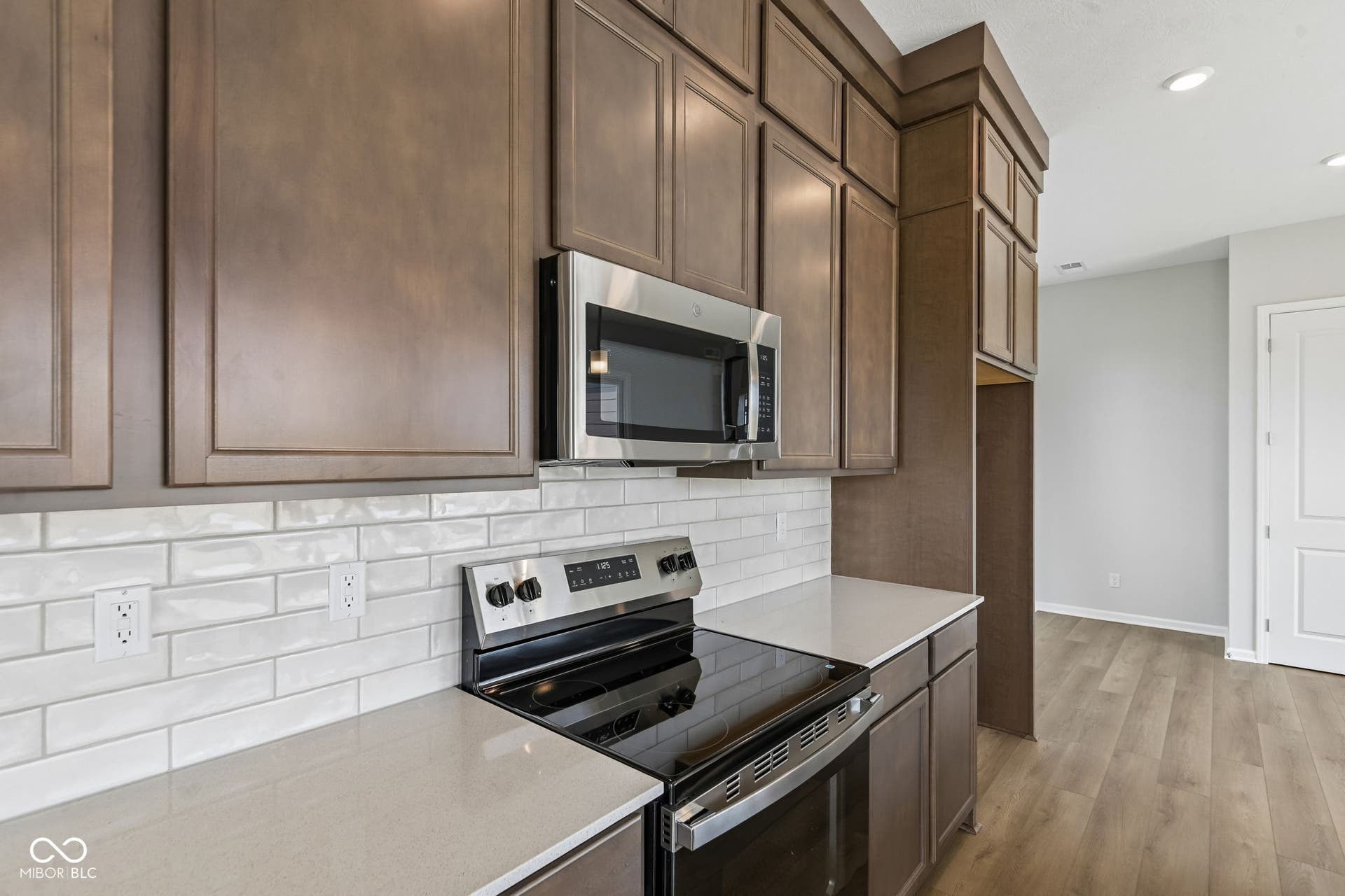 15762 Showdown Road, Noblesville, IN 46060 Kitchen featuring dark wood-finish cabinetry, stainless steel microwave, electric range, light-toned countertops, and a white subway tile backsplash