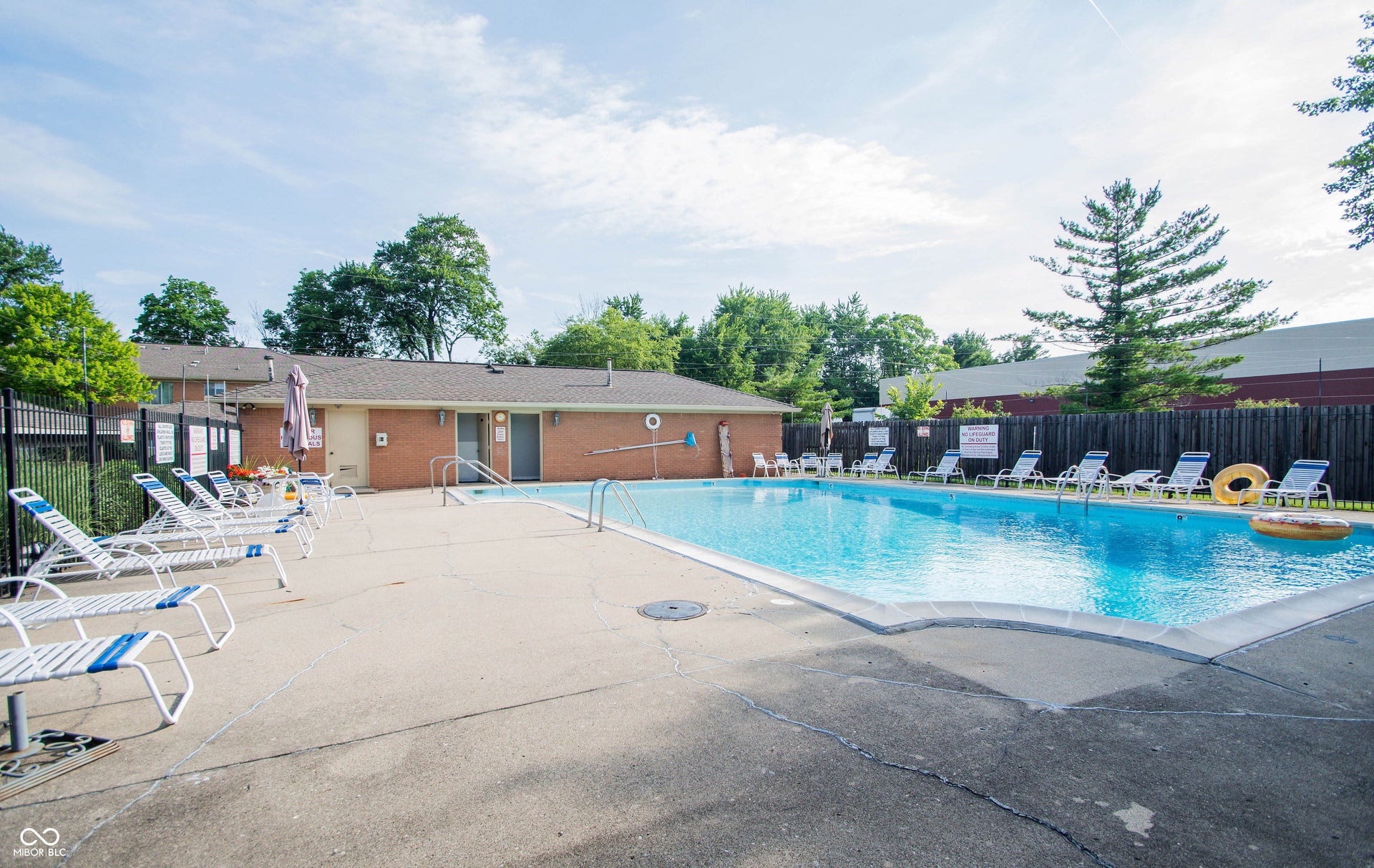 Community swimming pool featuring a perimeter fence and ample poolside decking