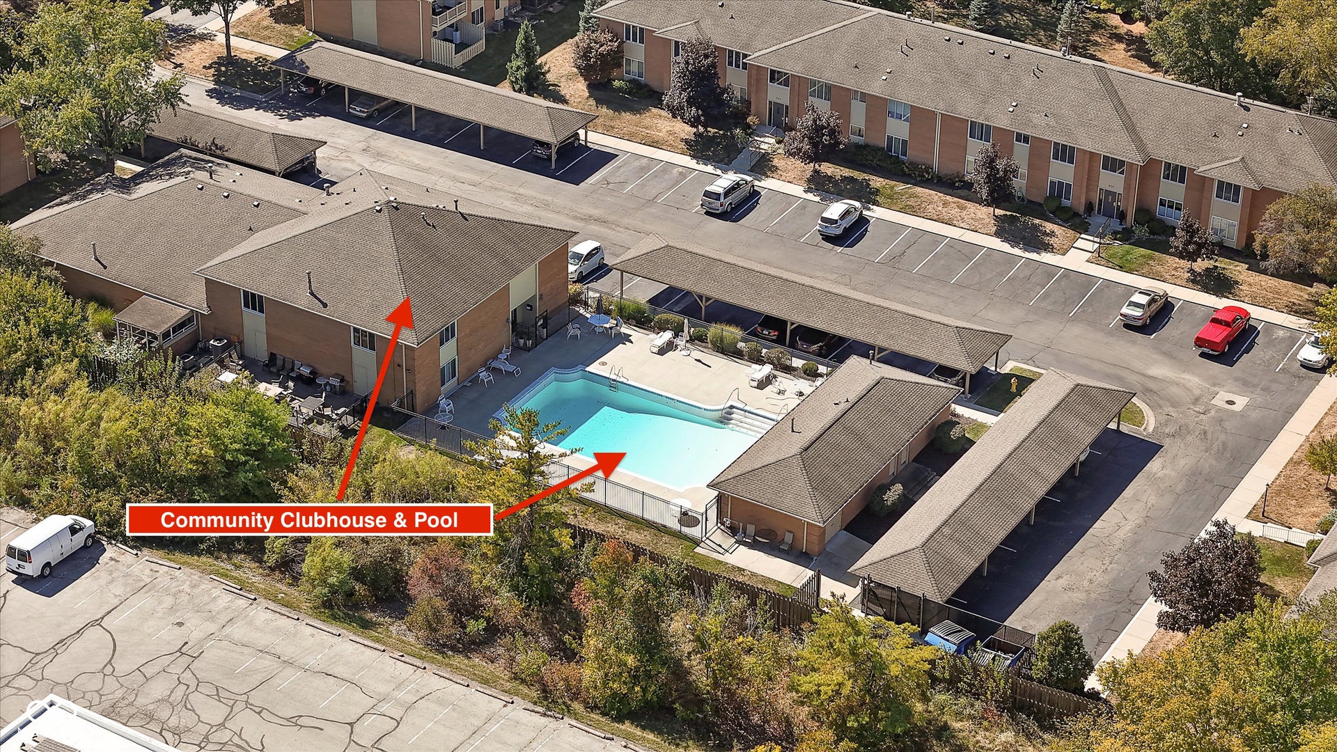 Community clubhouse with an outdoor swimming pool, surrounded by structured carports and surface parking