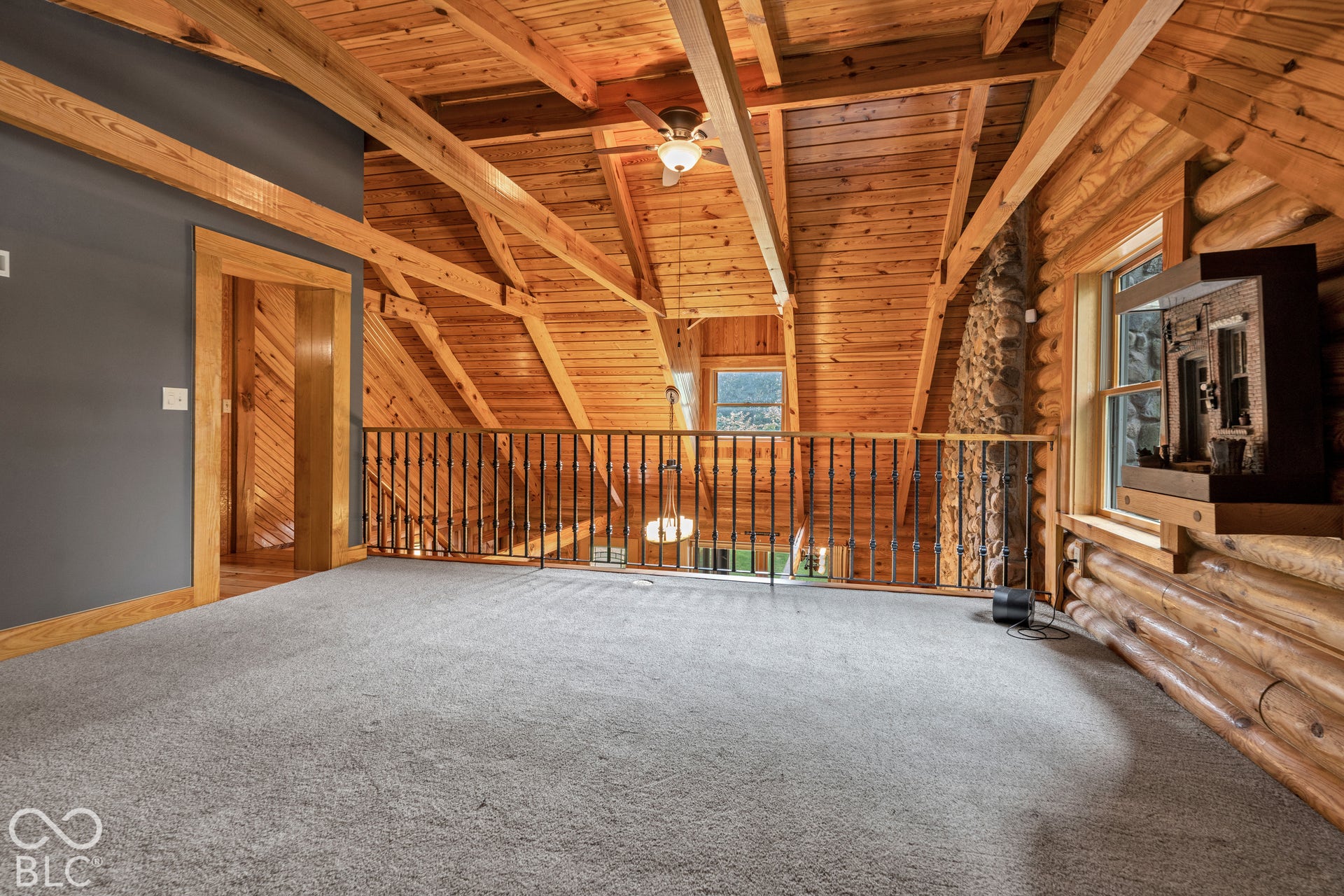 Vaulted wood-paneled ceilings with exposed beams, wood-finish log walls, and a stone-clad chimney feature