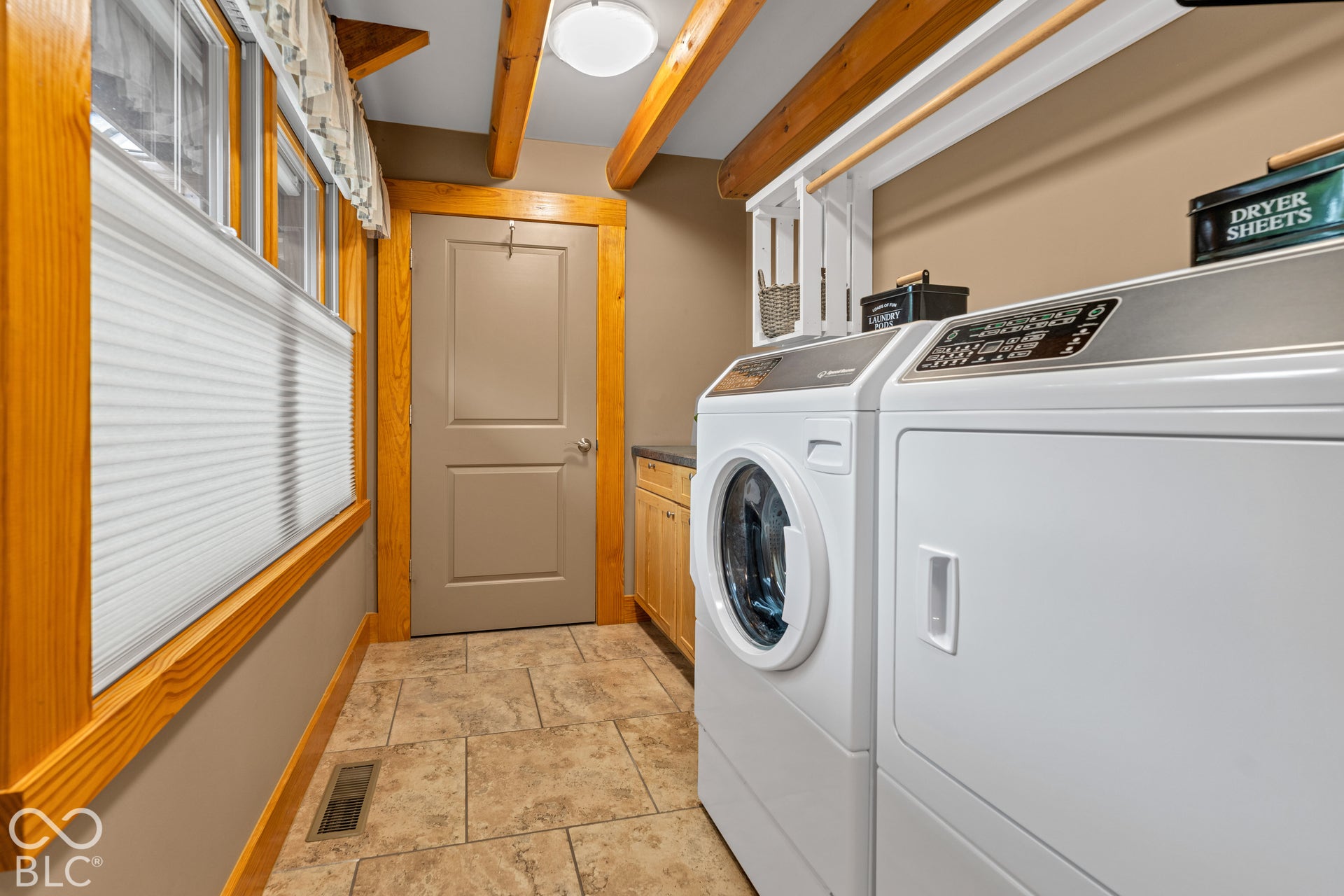 Tile flooring, natural wood window trim, exposed wood beams, built-in cabinetry, and overhead lighting