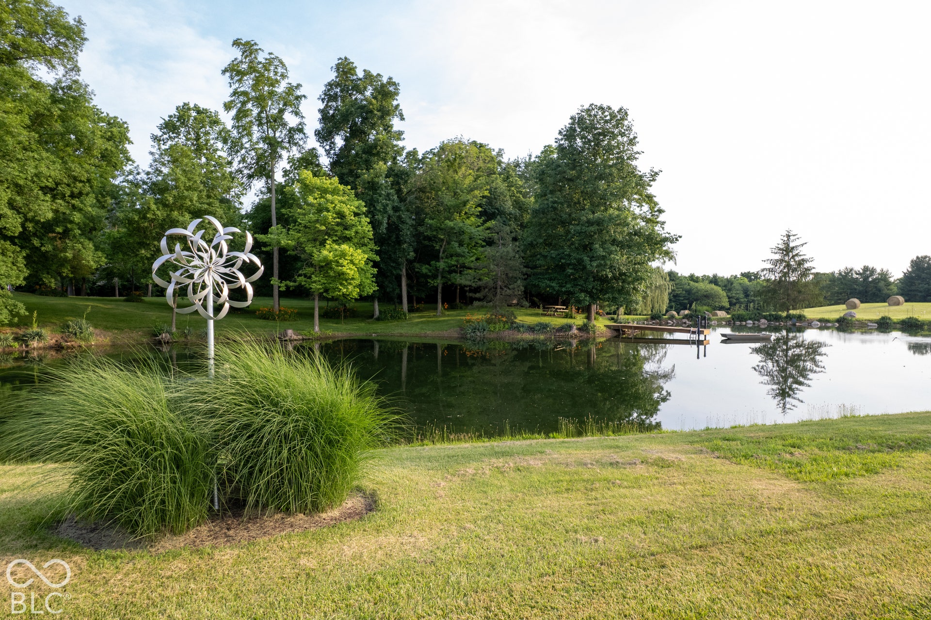 Expansive pond with a wooden dock and lush surrounding greenery