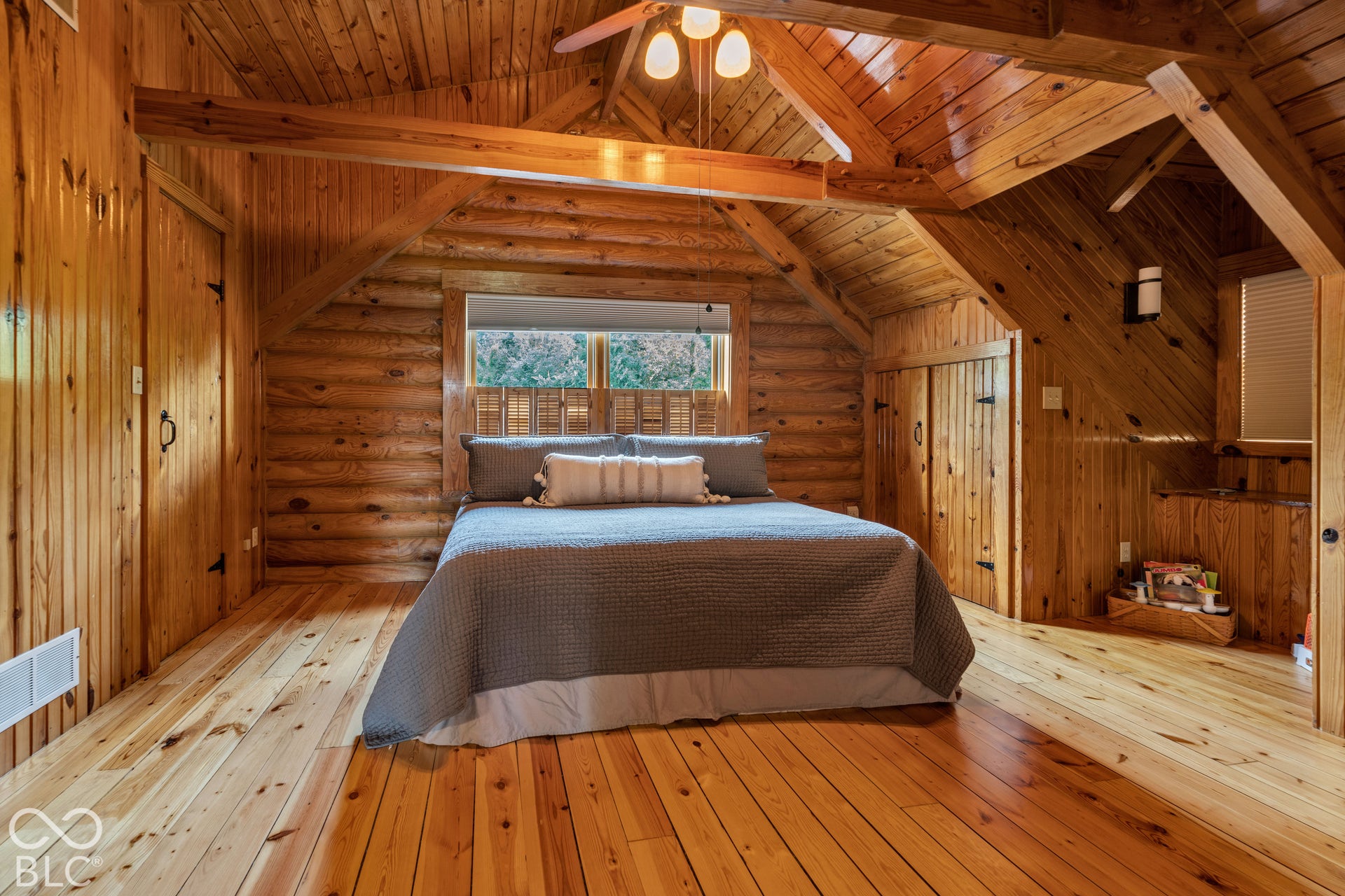 Wood-plank flooring throughout, log wall construction, exposed wood beam ceiling, wood-paneled walls, and built-in wood cabinetry