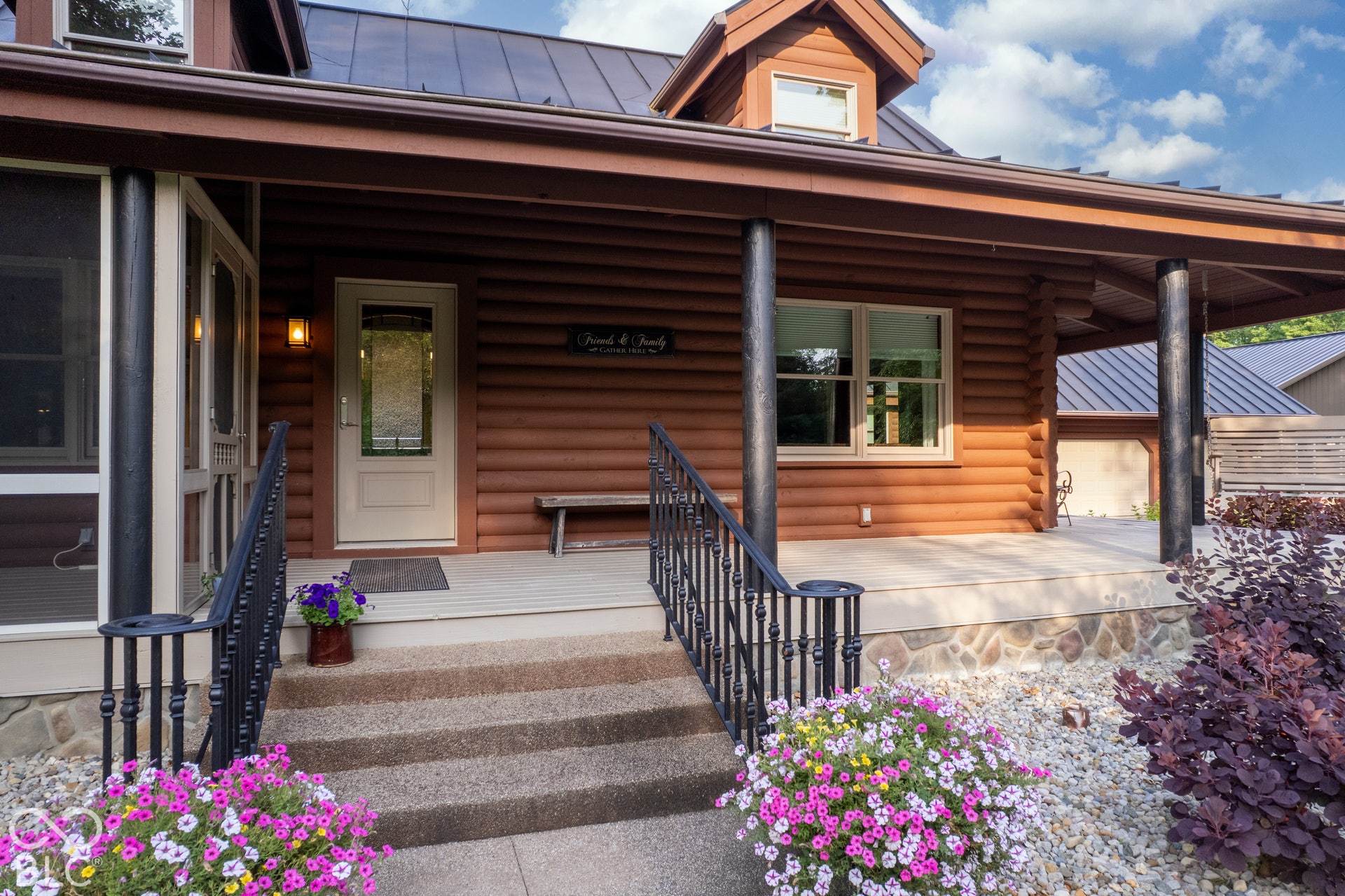 Log-style exterior with a covered porch featuring dark posts, stone accents, and a screened-in section