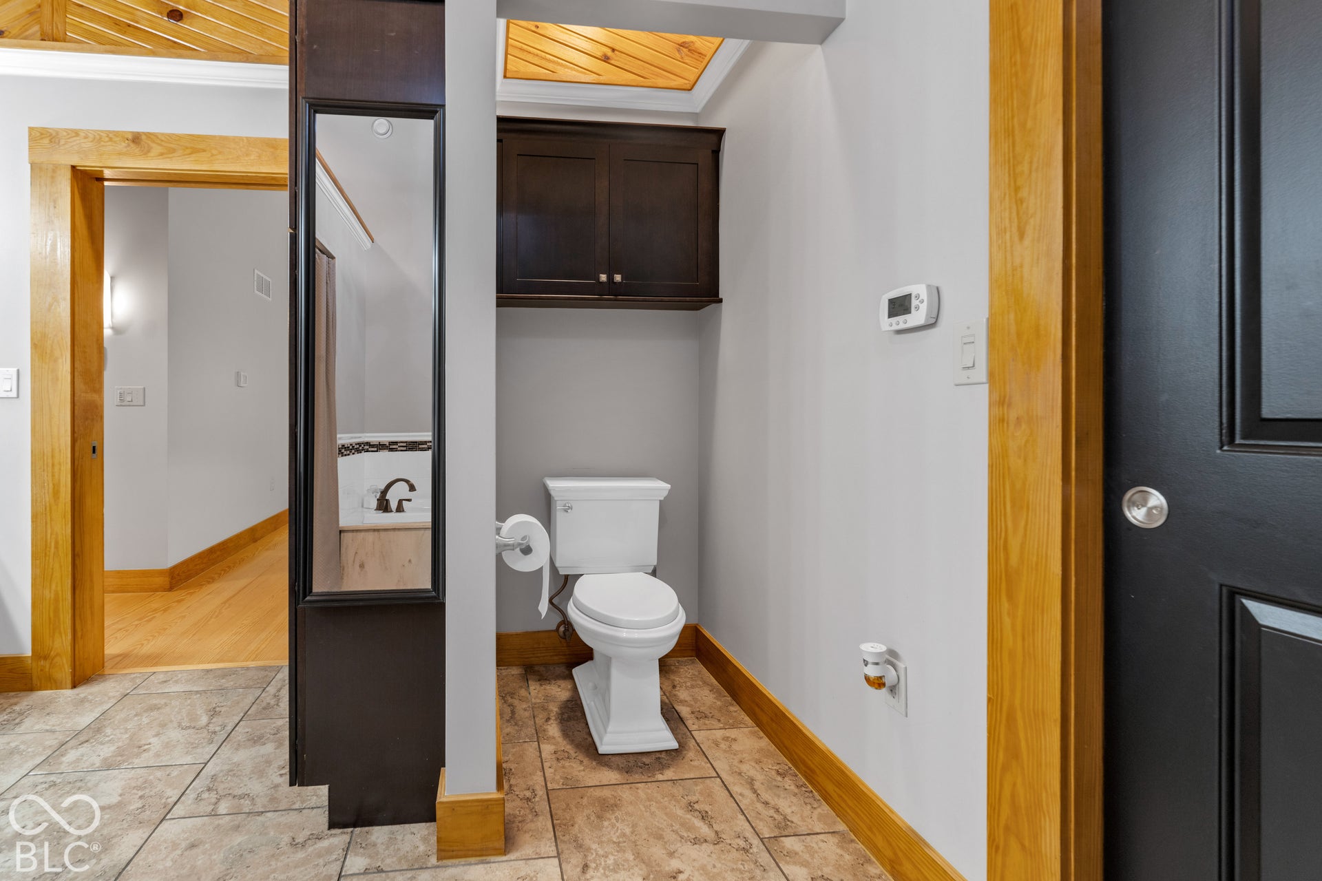 Recessed wooden ceiling, dark wood-finish cabinetry, tile flooring, and light wood-finish trim