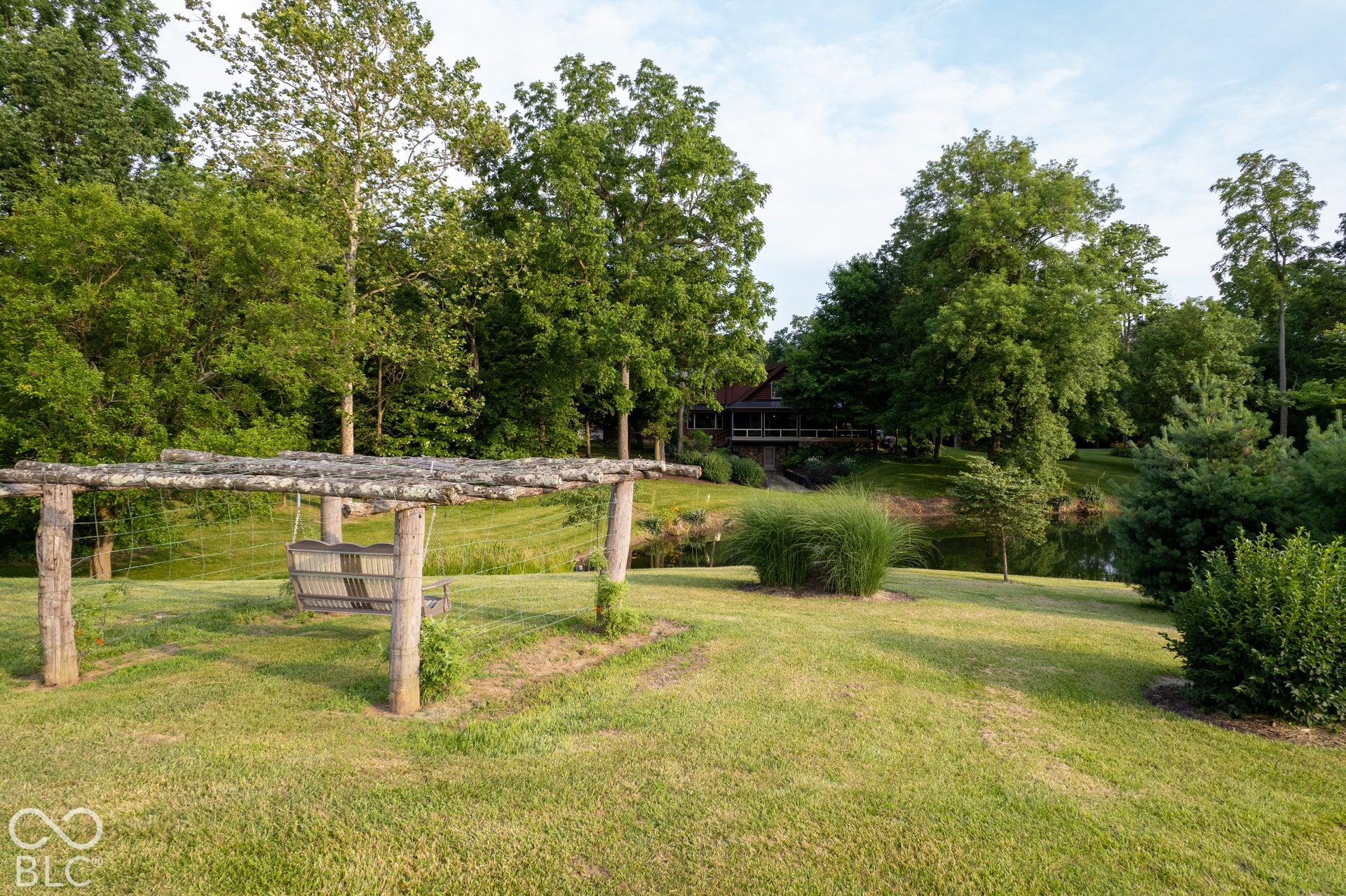 Manicured lawn with mature trees, established landscaping, and a tranquil pond