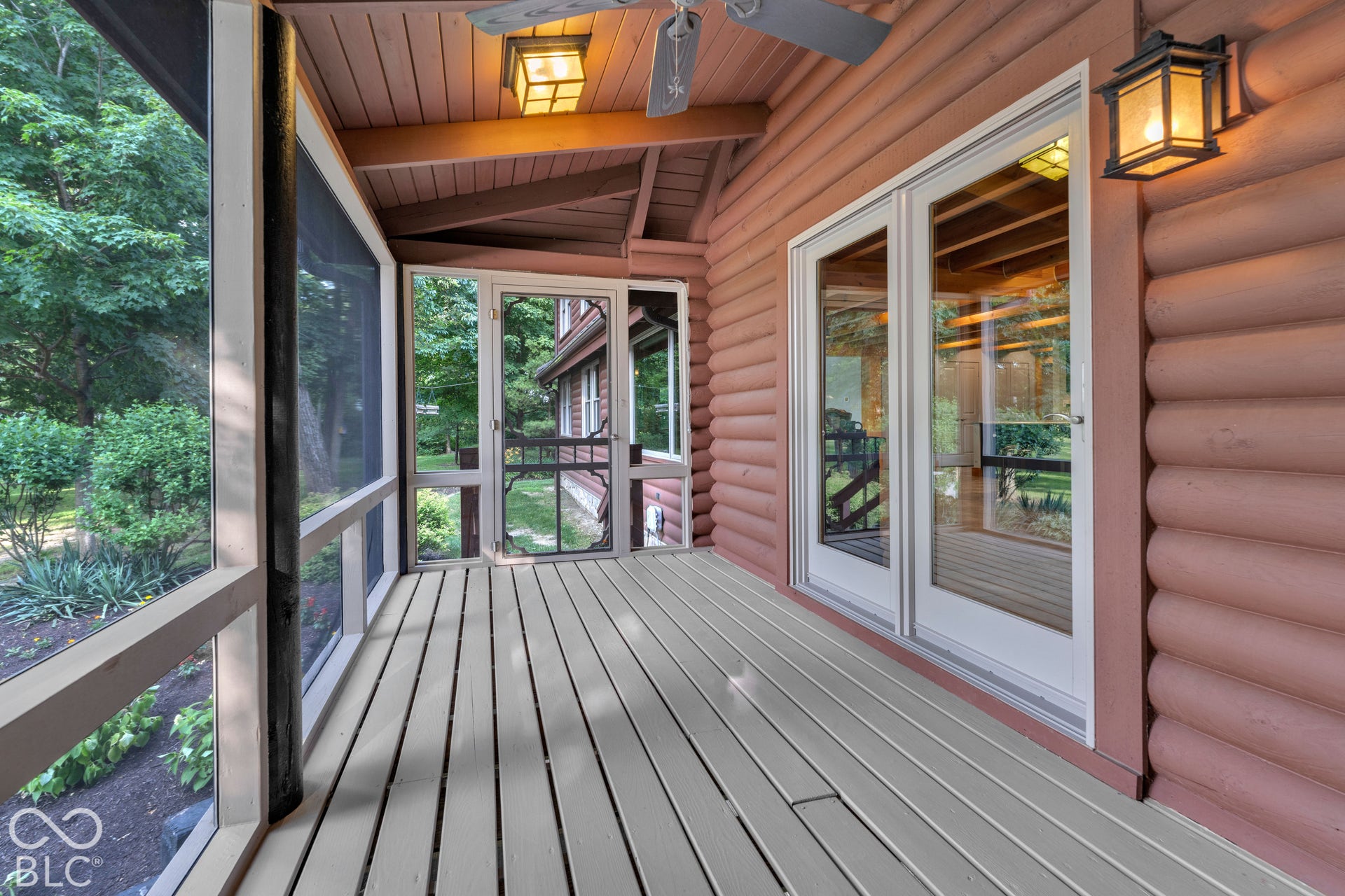 Screened porch featuring light-toned wood-finish flooring, log-style exterior siding, and white-framed glass doors