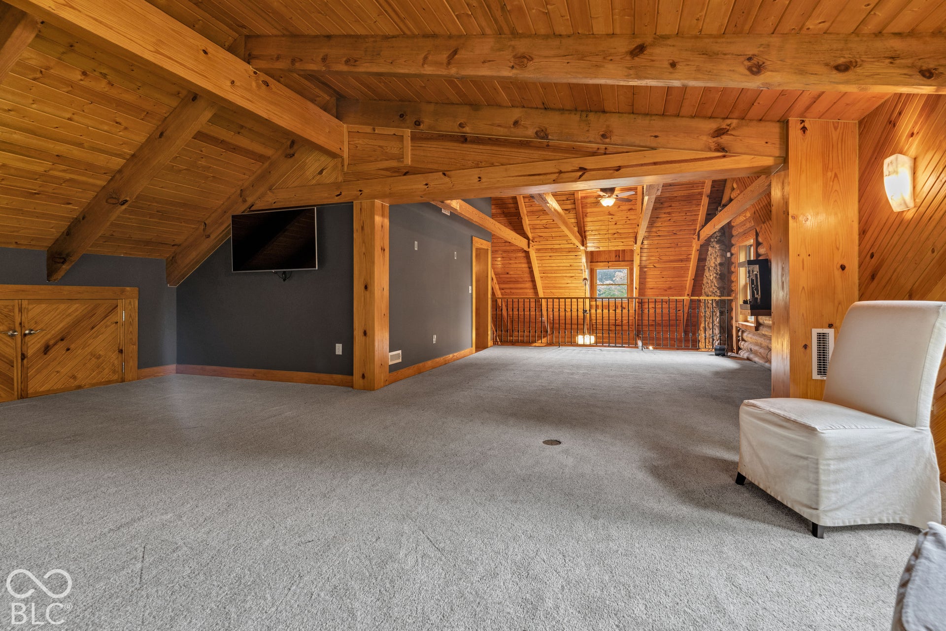Wood-paneled vaulted ceilings with exposed beams, wood-finish built-in cabinetry, and gray carpeting