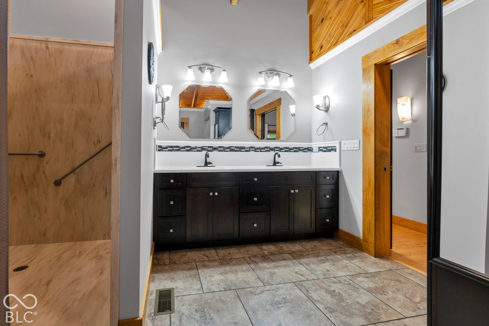 Dual vanity with dark wood-finish cabinetry, white countertop, and contemporary hexagonal mirrors