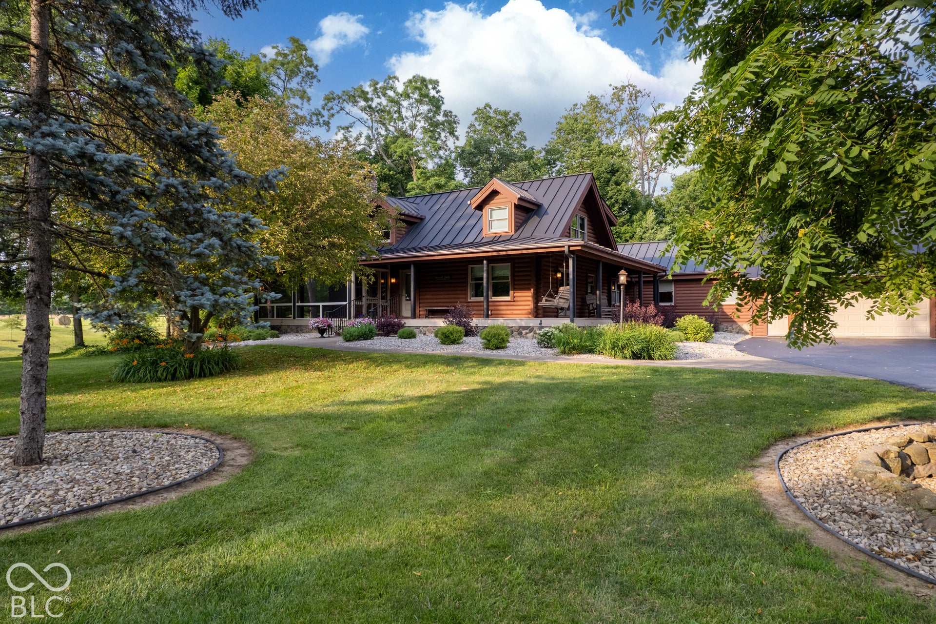 Wood-sided residence with a dark metal roof, front porch, and dormer window