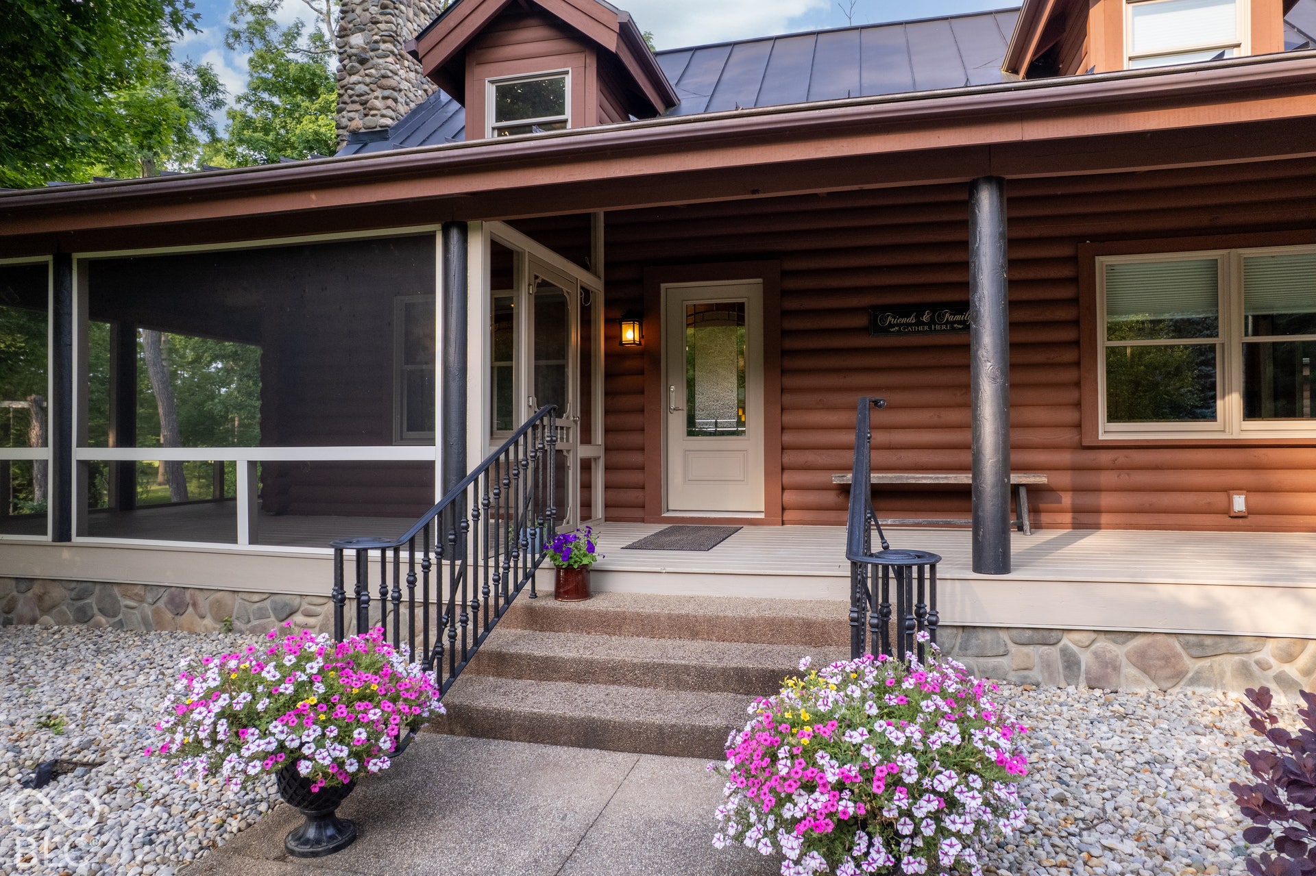 Log-style exterior with a screened porch, stone chimney, and a durable metal roof