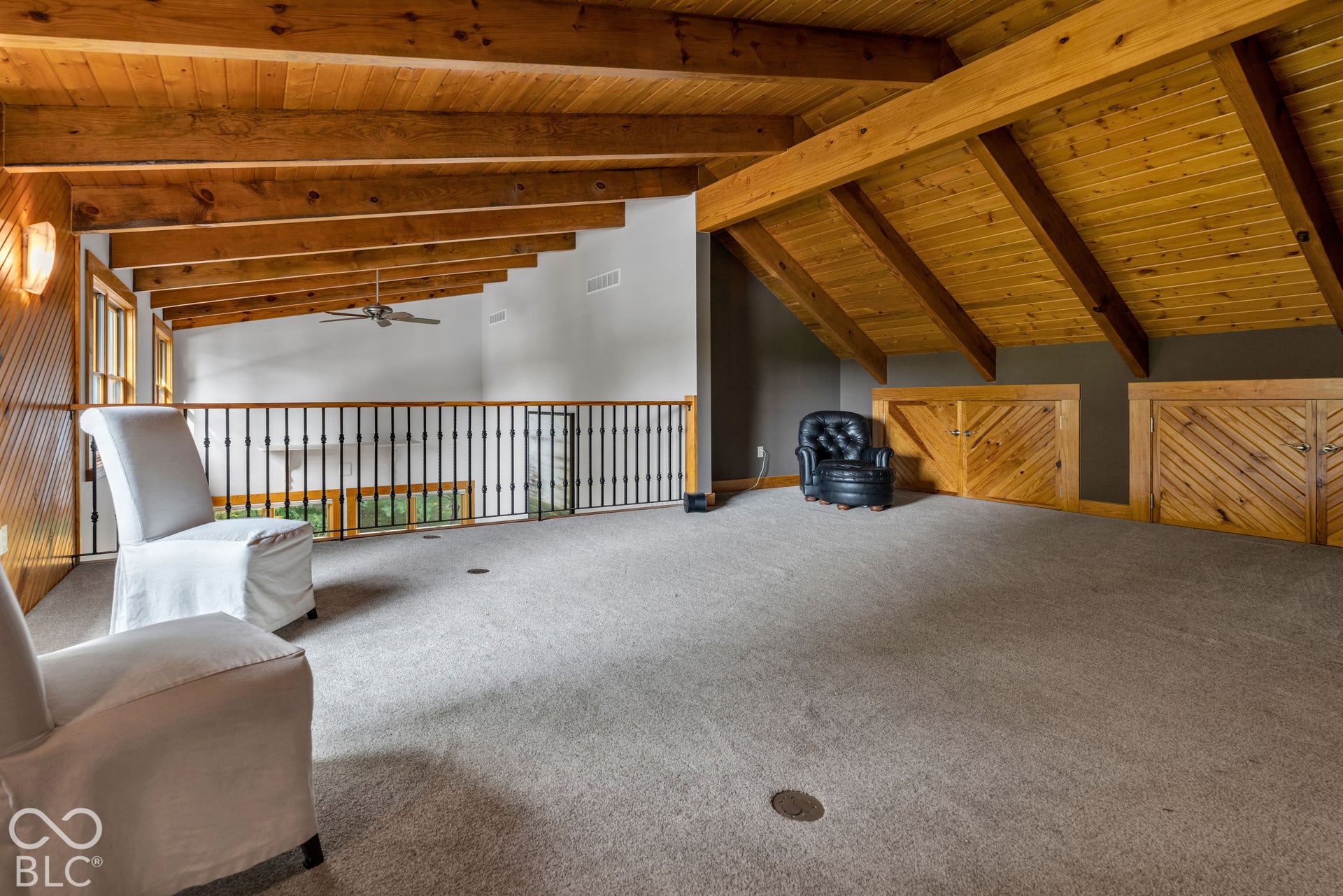 Exposed wood beam ceiling, vaulted wood ceiling, carpeted flooring, wood-paneled walls, built-in cabinetry