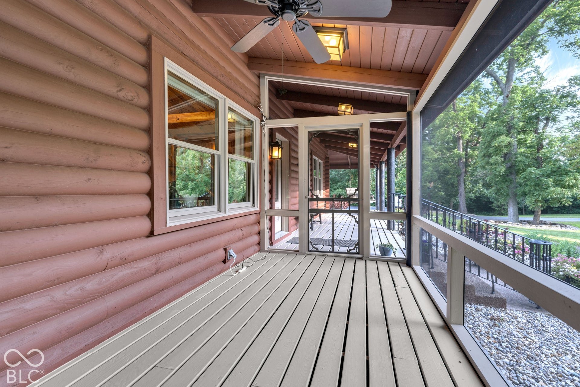 Screened porch with wood-finish flooring, log exterior siding, and a ceiling fan