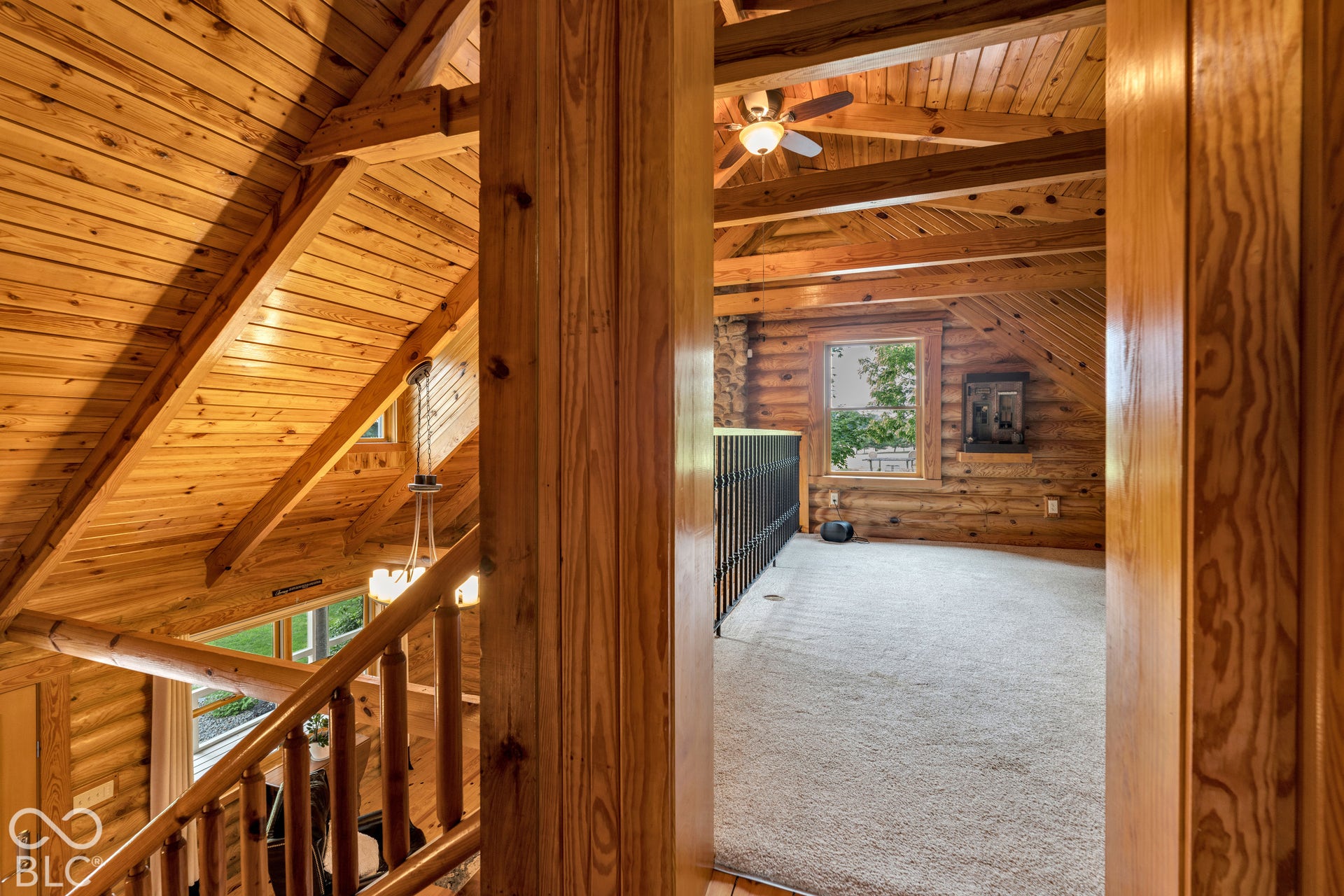 Vaulted wood-paneled ceilings with exposed beams, wood-finish walls, ceiling fan, carpeted flooring, and a large window