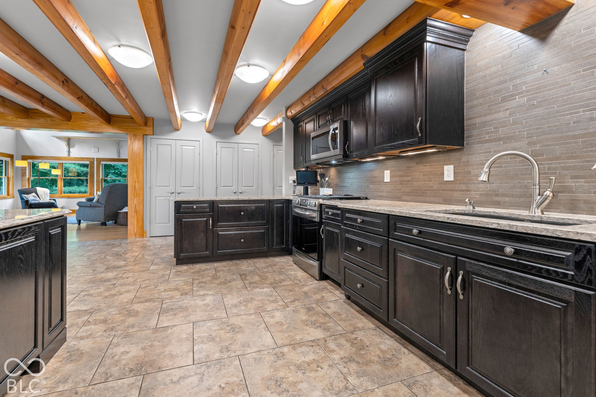 Kitchen with dark wood-finish cabinetry, light-toned countertops, a tile backsplash, and stainless steel appliances