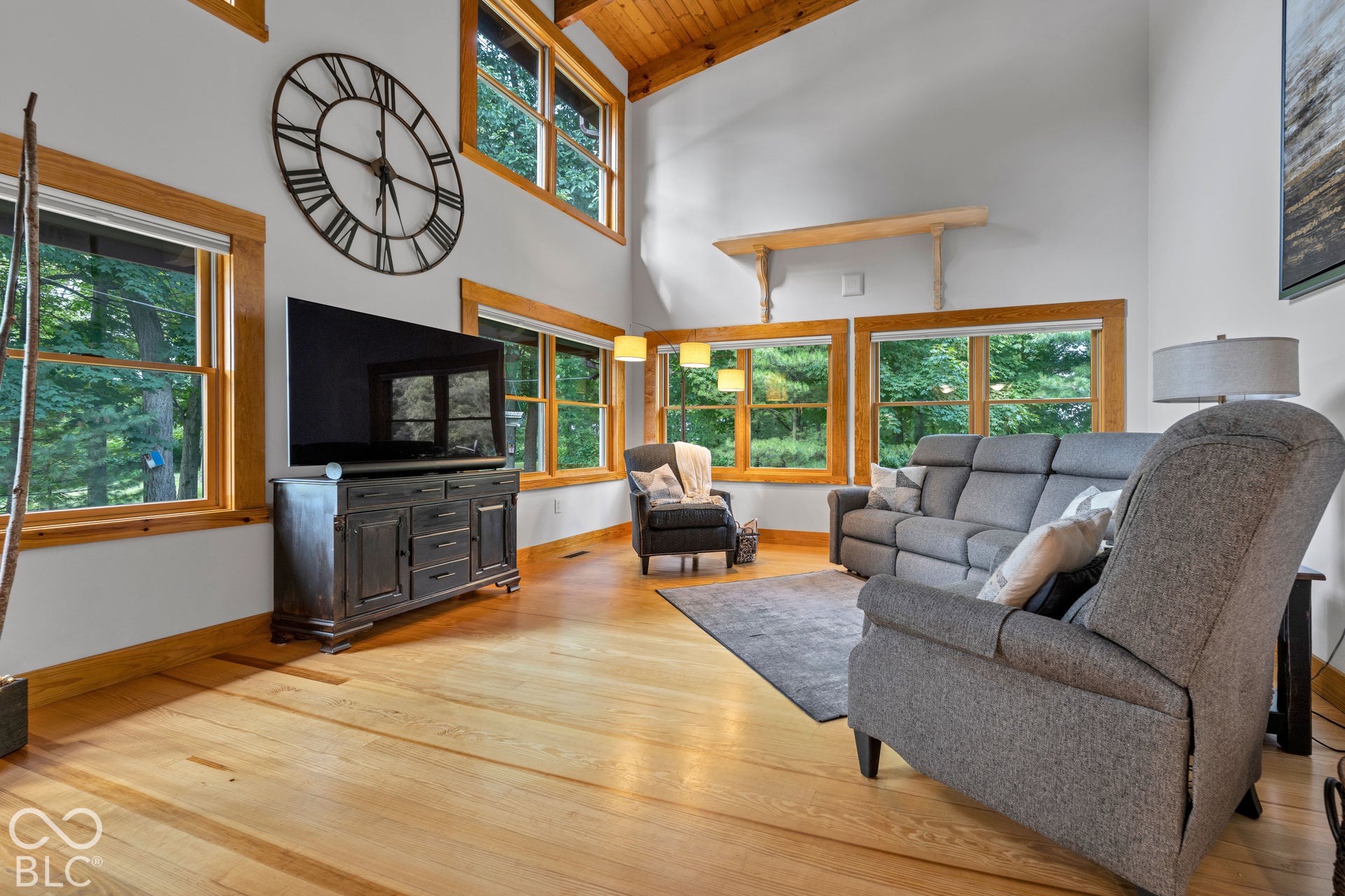 Vaulted ceiling with wood-finish planks, wood-finish flooring, and multiple windows with wood-finish trim
