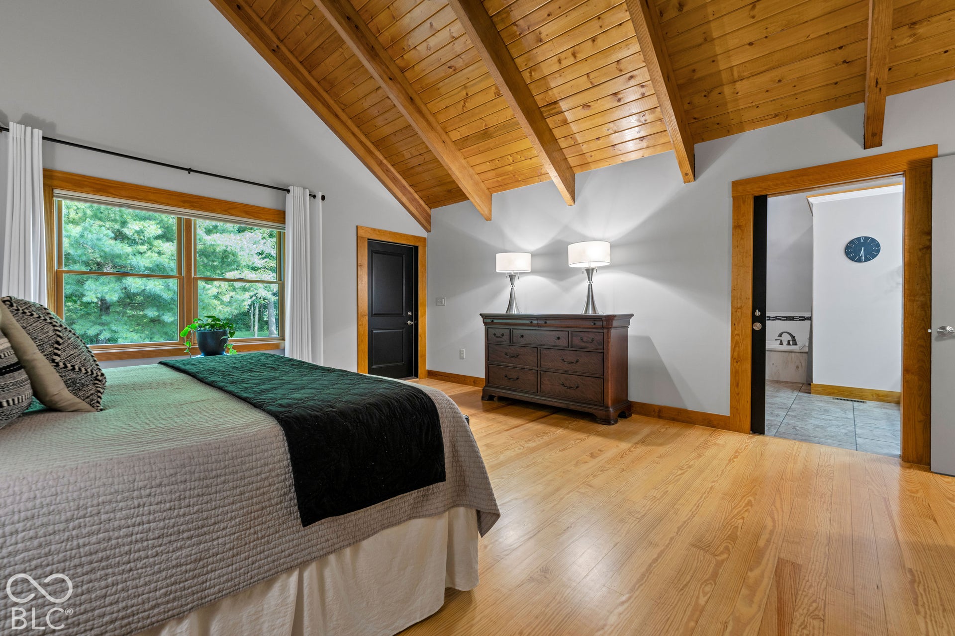 Vaulted wood-paneled ceilings, natural wood-finish flooring, and large windows with wood trim