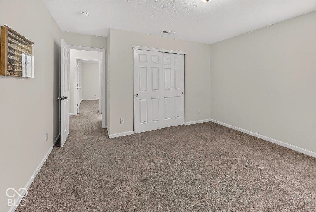Carpeted interior space featuring light-toned walls and a white paneled bi-fold closet