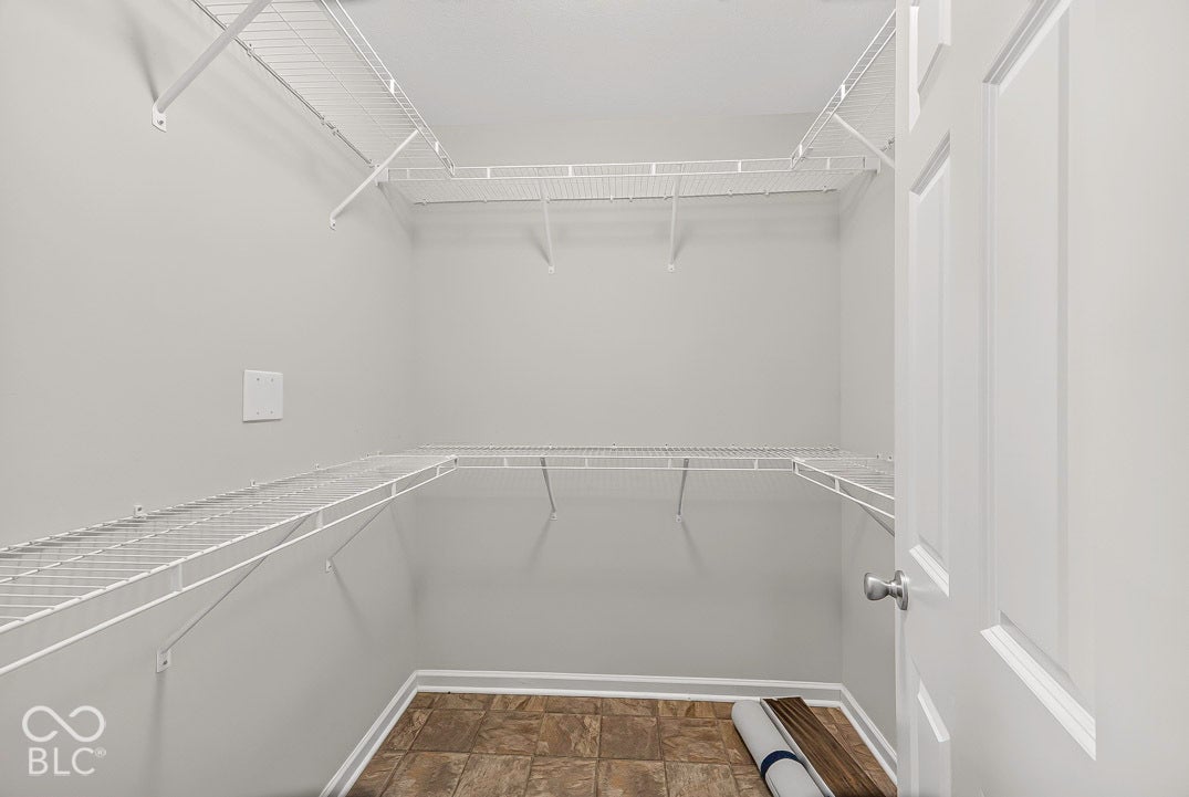 Walk-in closet featuring wire shelving, panel door, and tile flooring