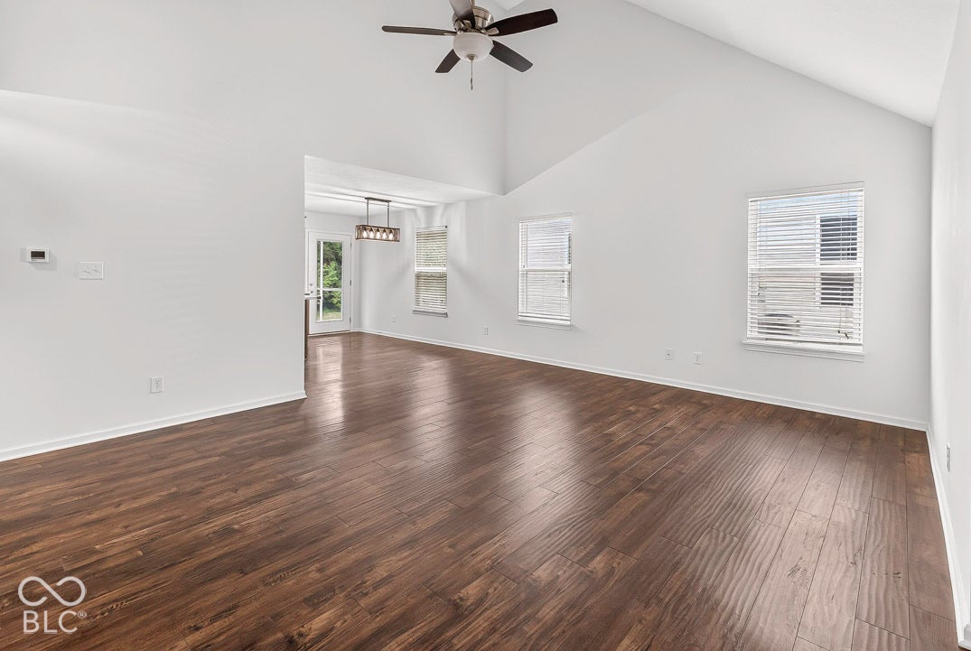 Vaulted ceiling, wood-finish flooring, ceiling fan, multiple windows, and recessed lighting