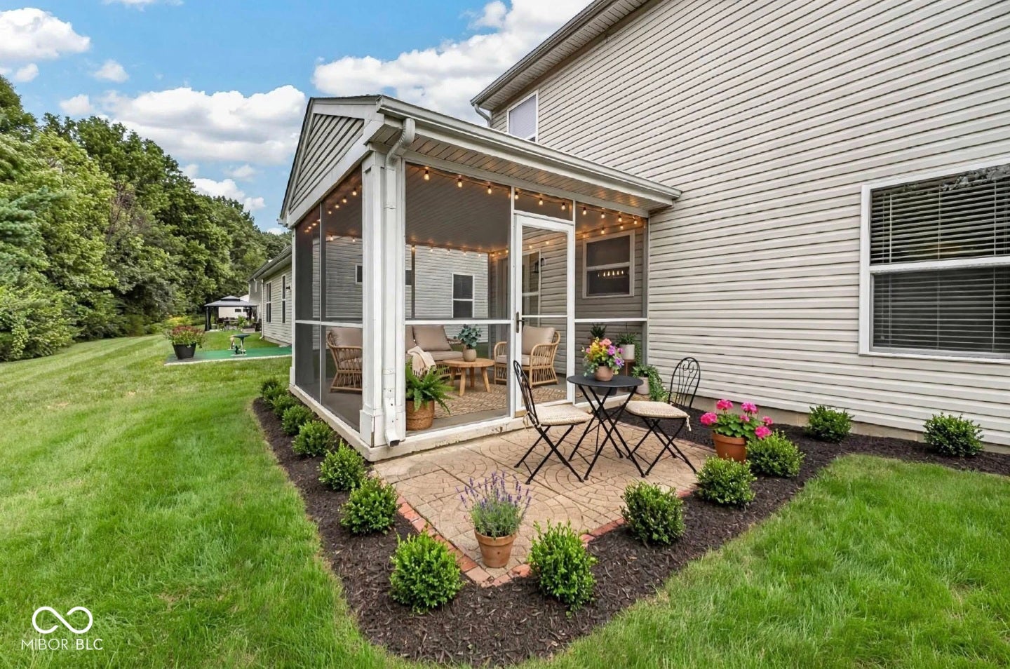 Screened porch, exterior patio, manicured landscaping, and expansive green space
