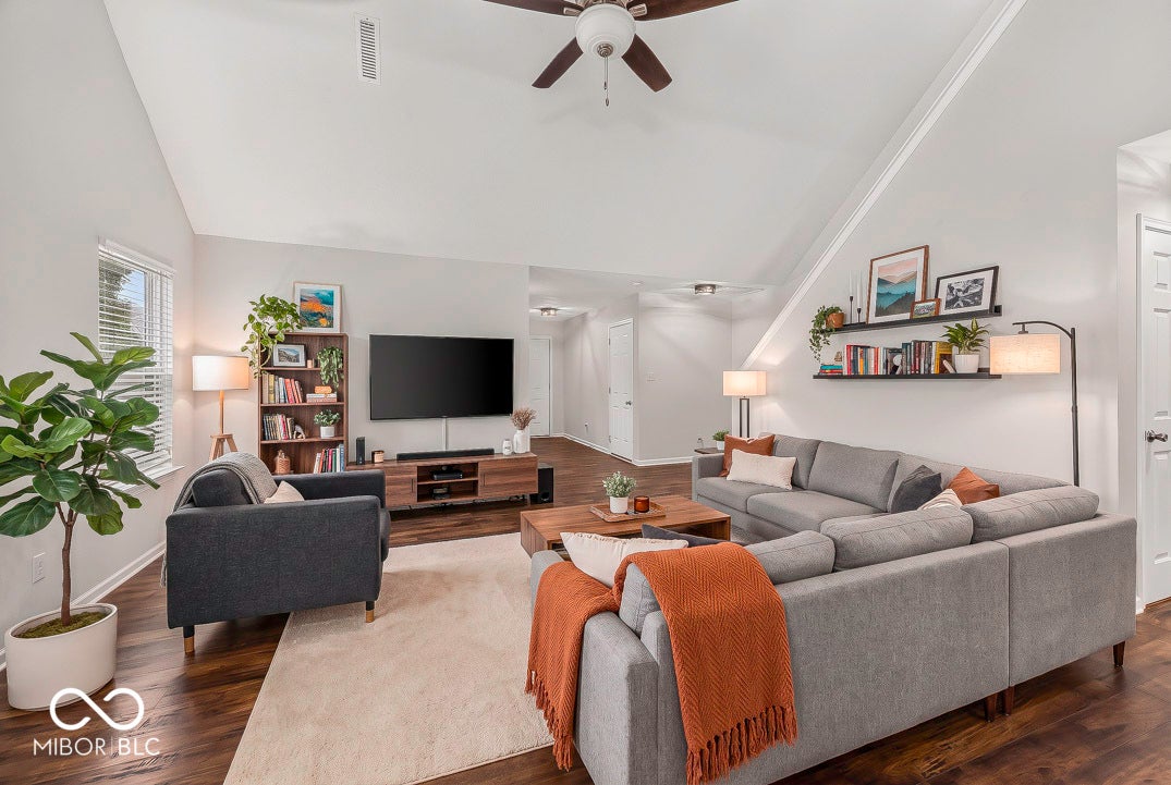 Vaulted ceiling with a ceiling fan, dark wood-finish flooring, and light-toned walls