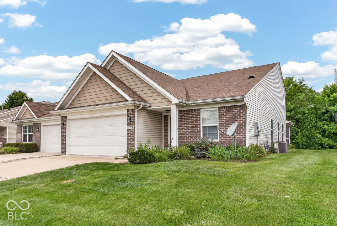 Brick and siding exterior with shingle roof, attached two-car garage, and established landscaping